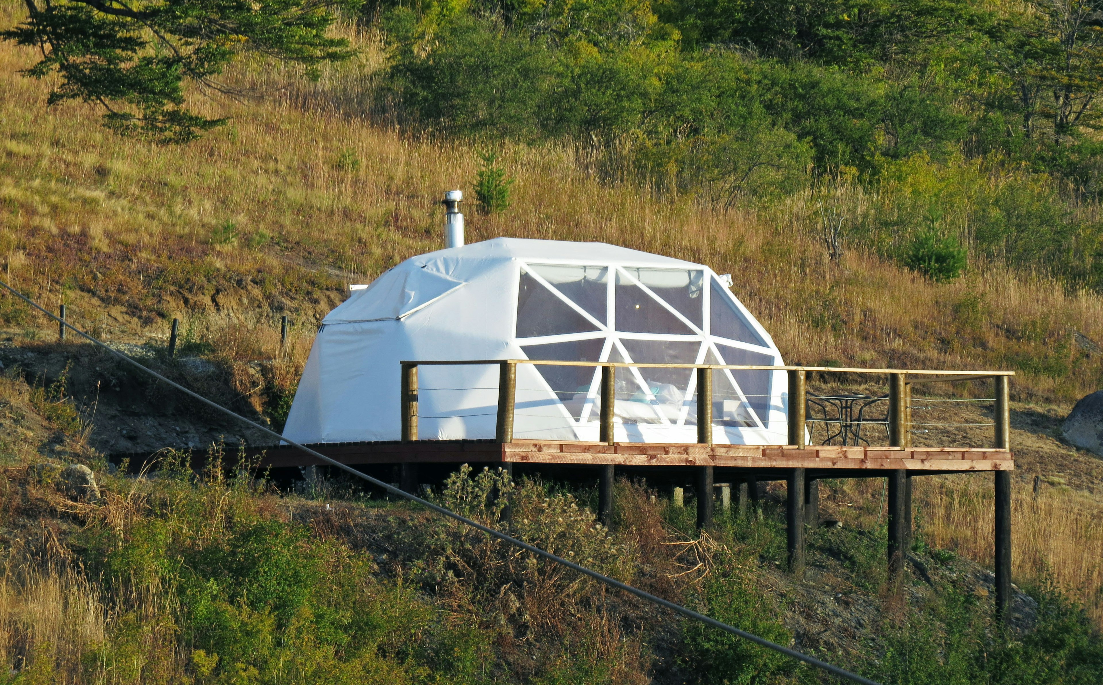 一座白色的几何圆顶建筑位于草地上的山坡上