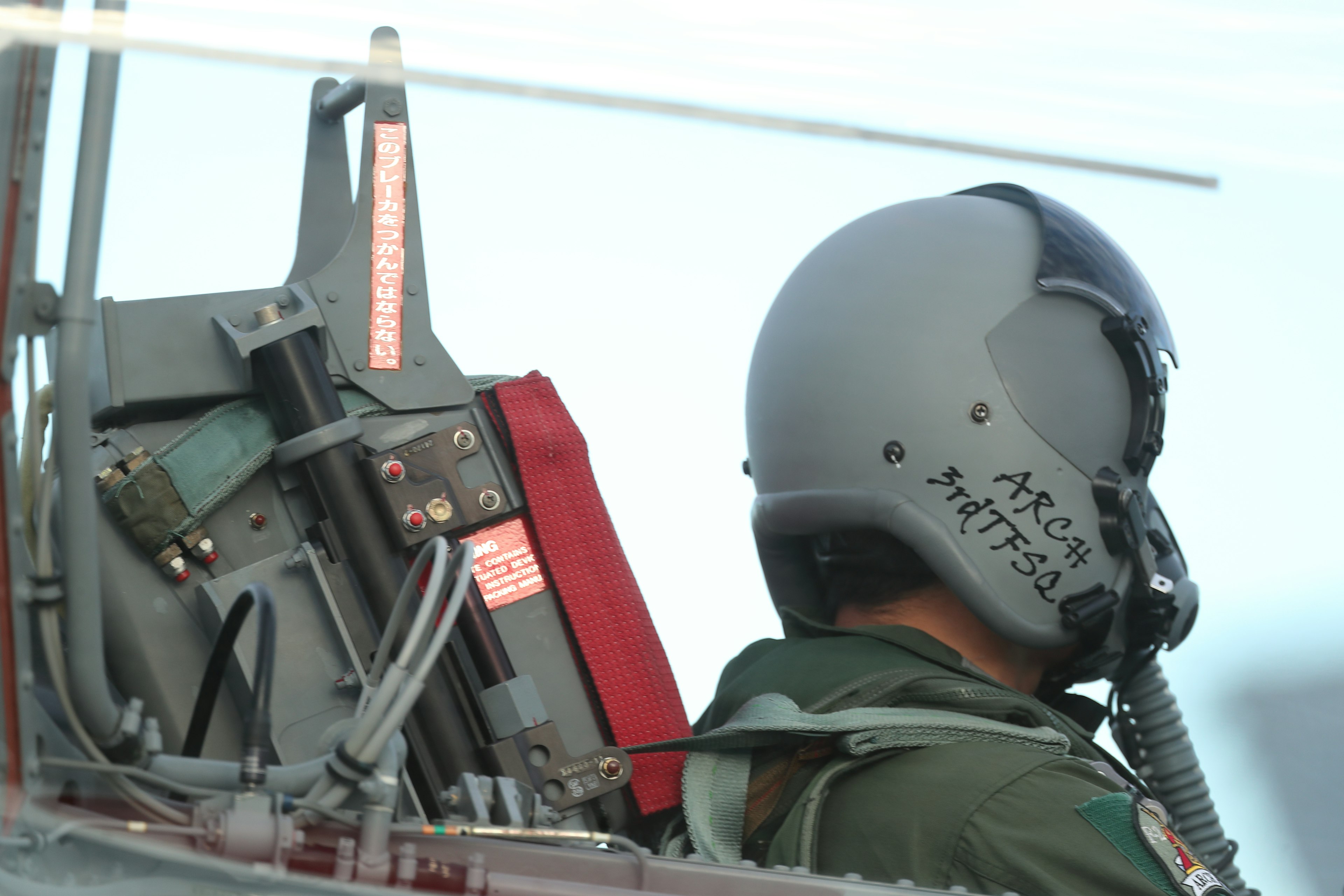 Pilot in cockpit with helmet and equipment visible