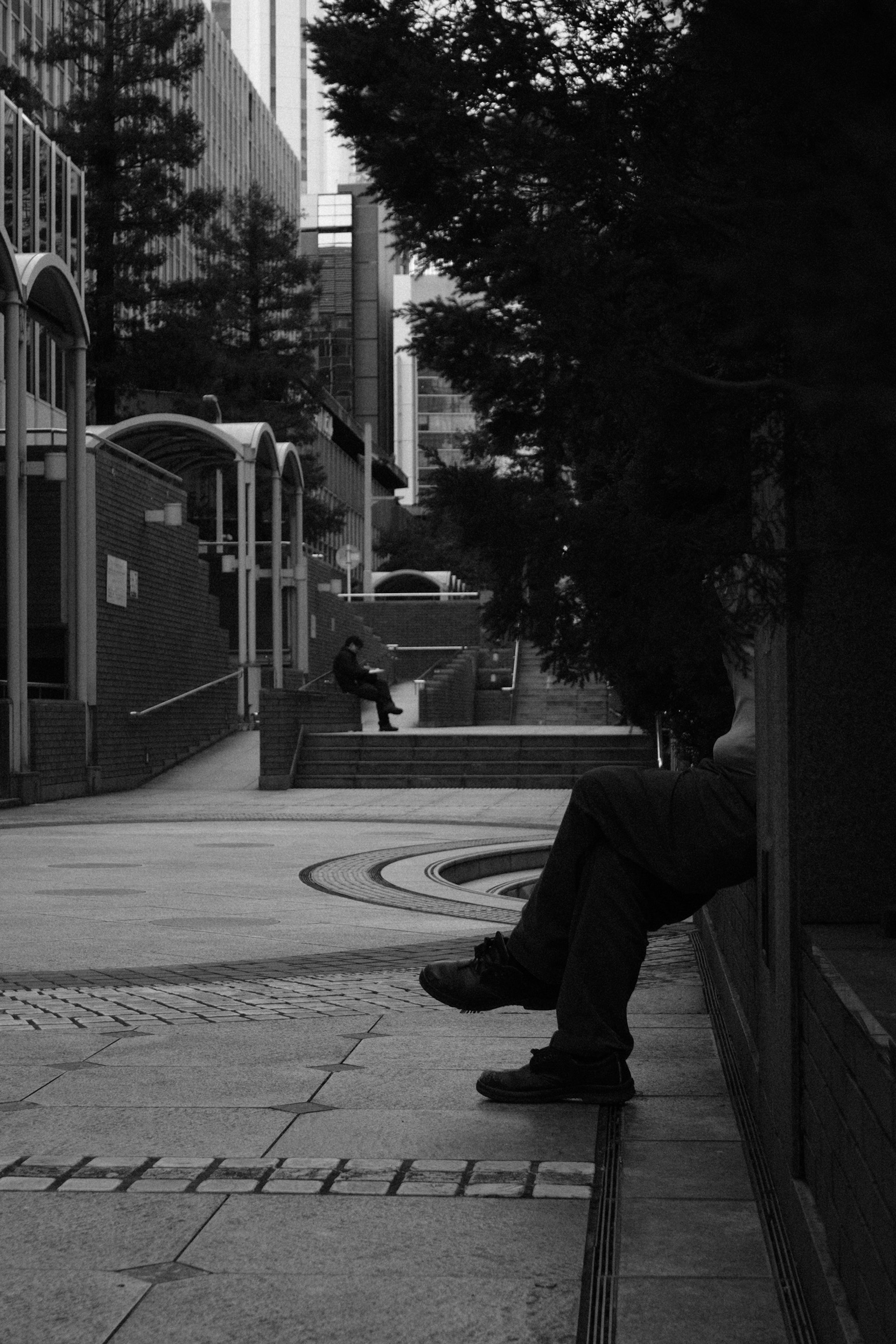 Silhouette of a person sitting on a bench in a quiet urban setting