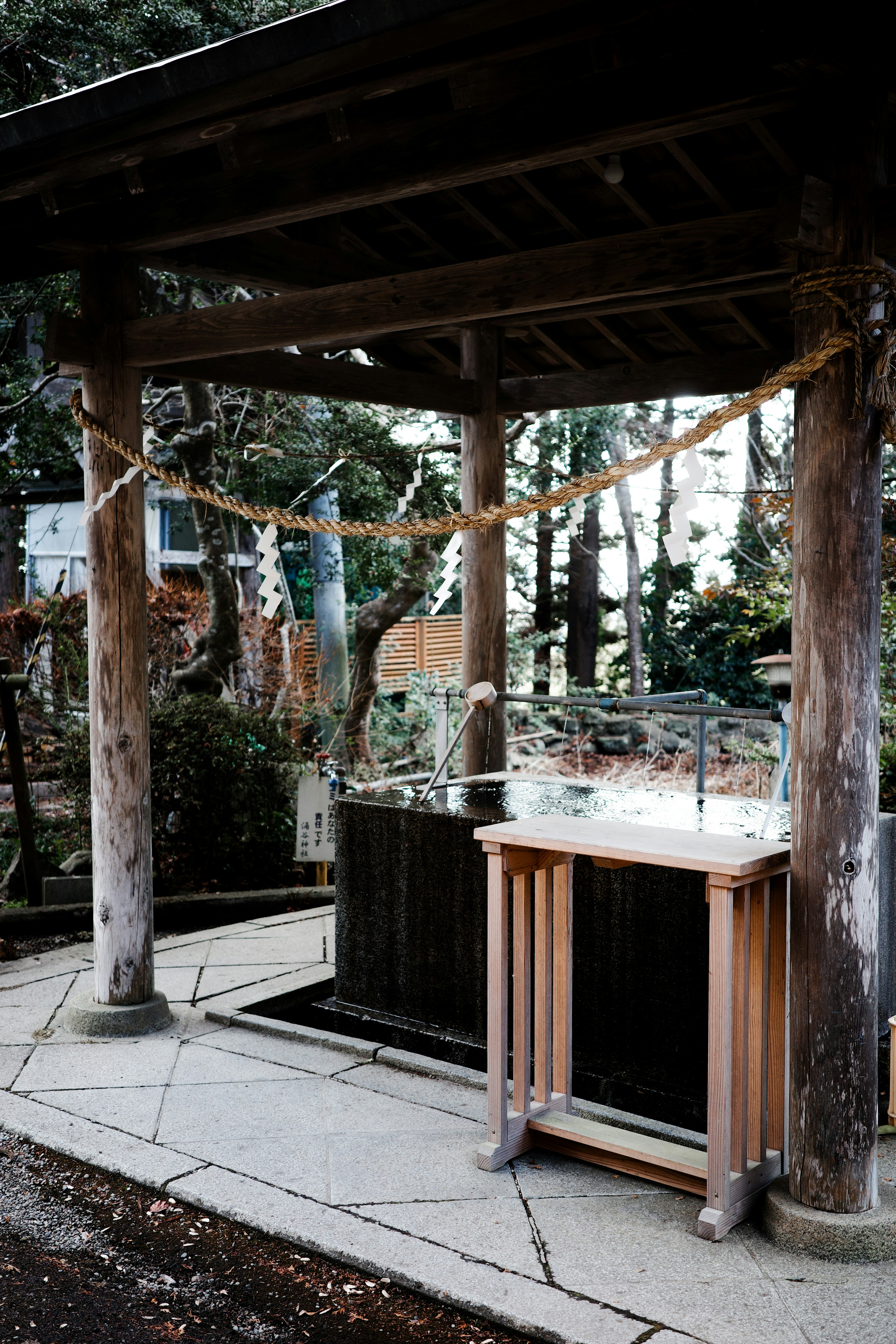 A shrine scene featuring a purification water basin and altar under a wooden roof