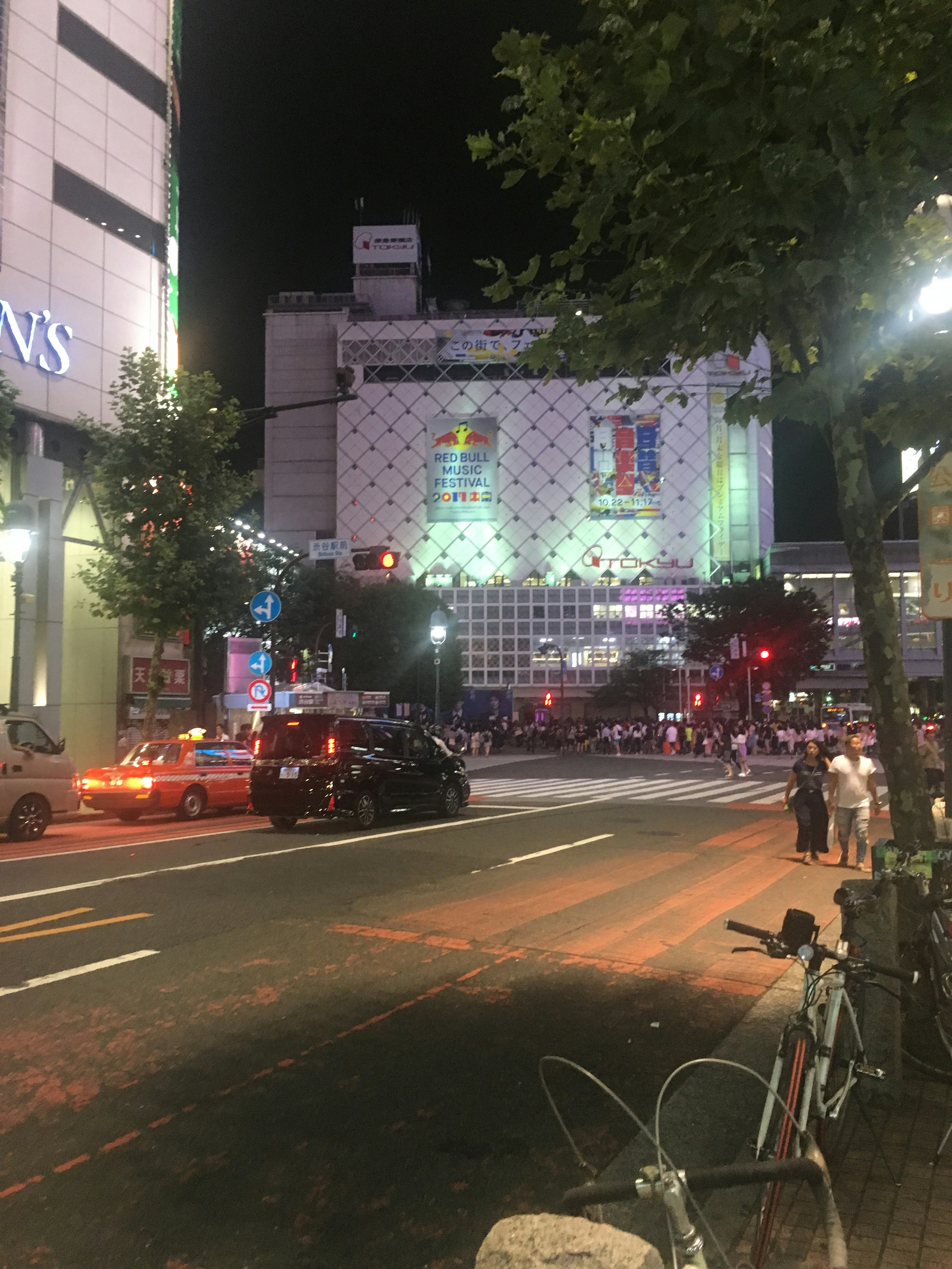 Nighttime street scene in Shibuya with traffic and illuminated buildings