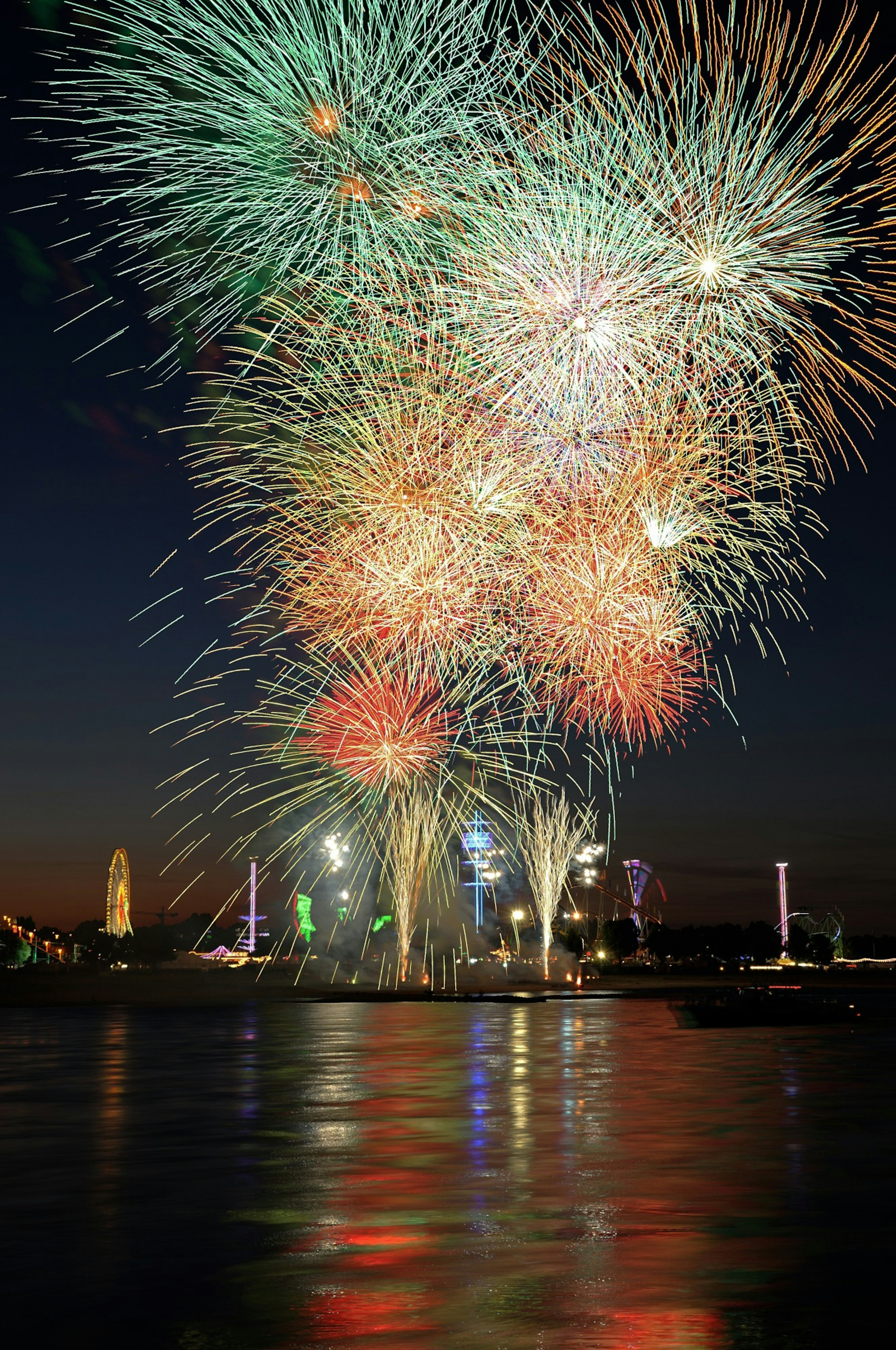 Colorful fireworks bursting in the night sky reflecting on the water