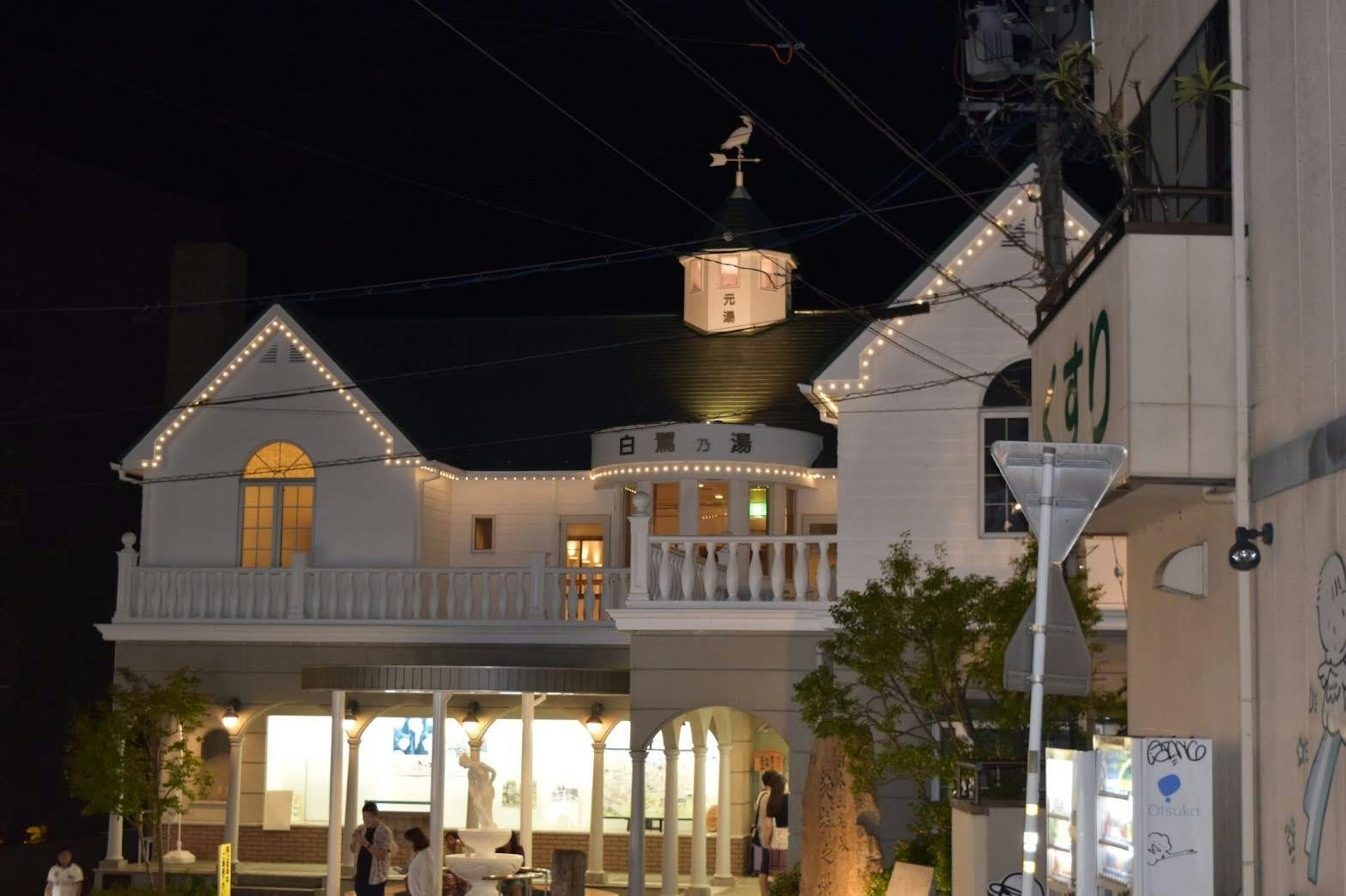 Night view of a white building with distinctive balcony and weather vane