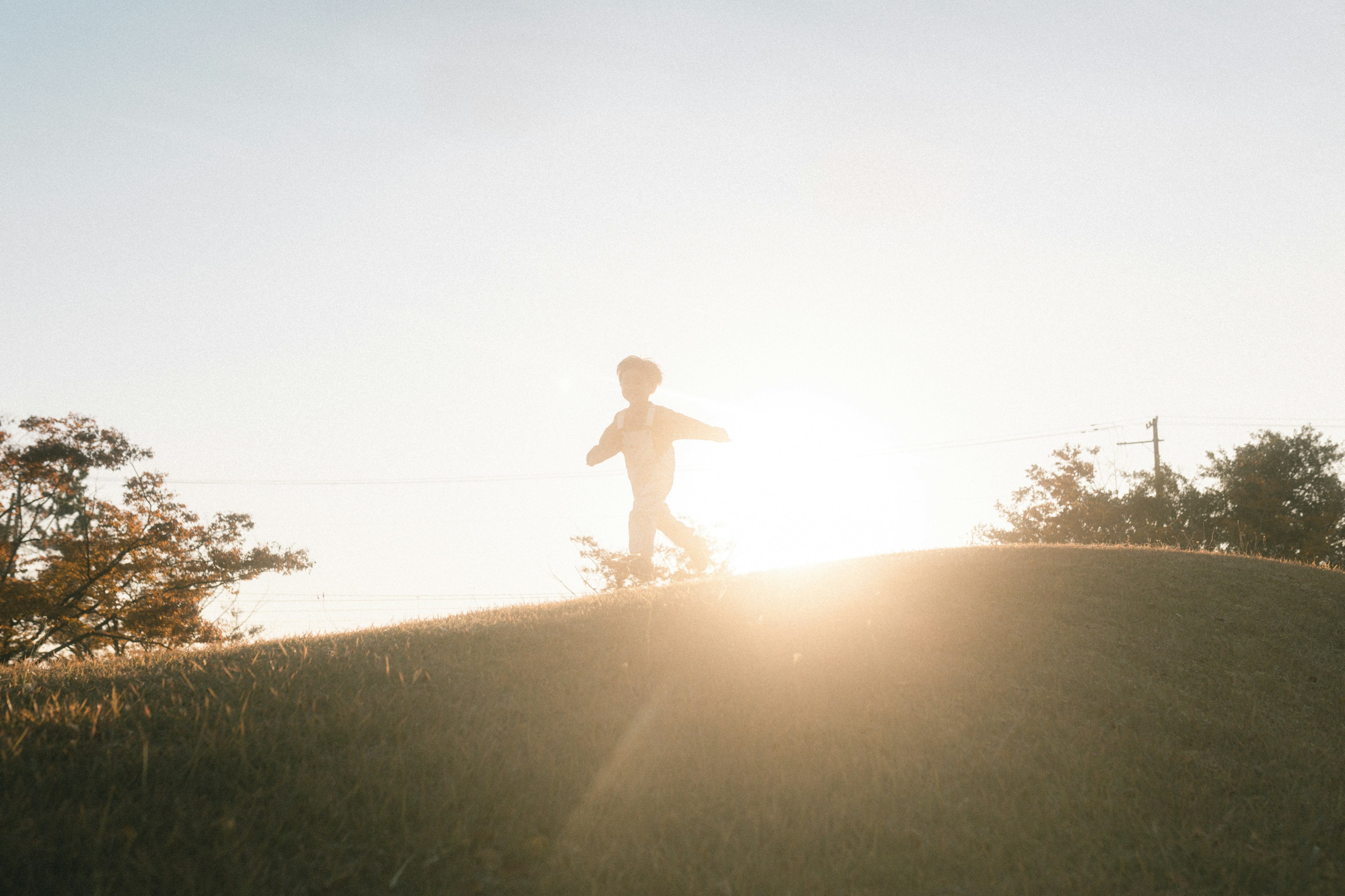 Silueta de un niño corriendo en una colina contra el atardecer