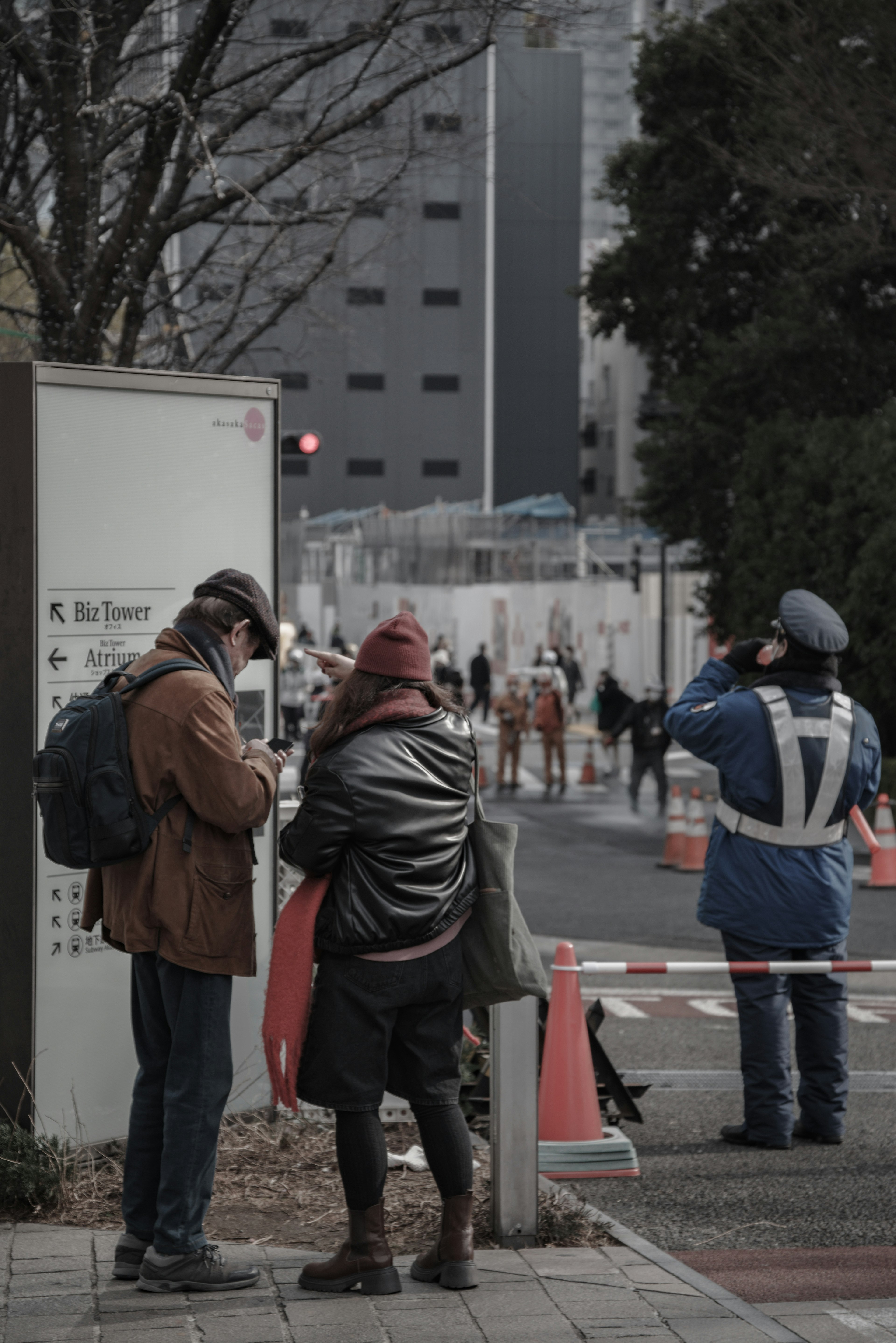 Dos personas usando un smartphone en una esquina de la calle con un oficial de tráfico cerca