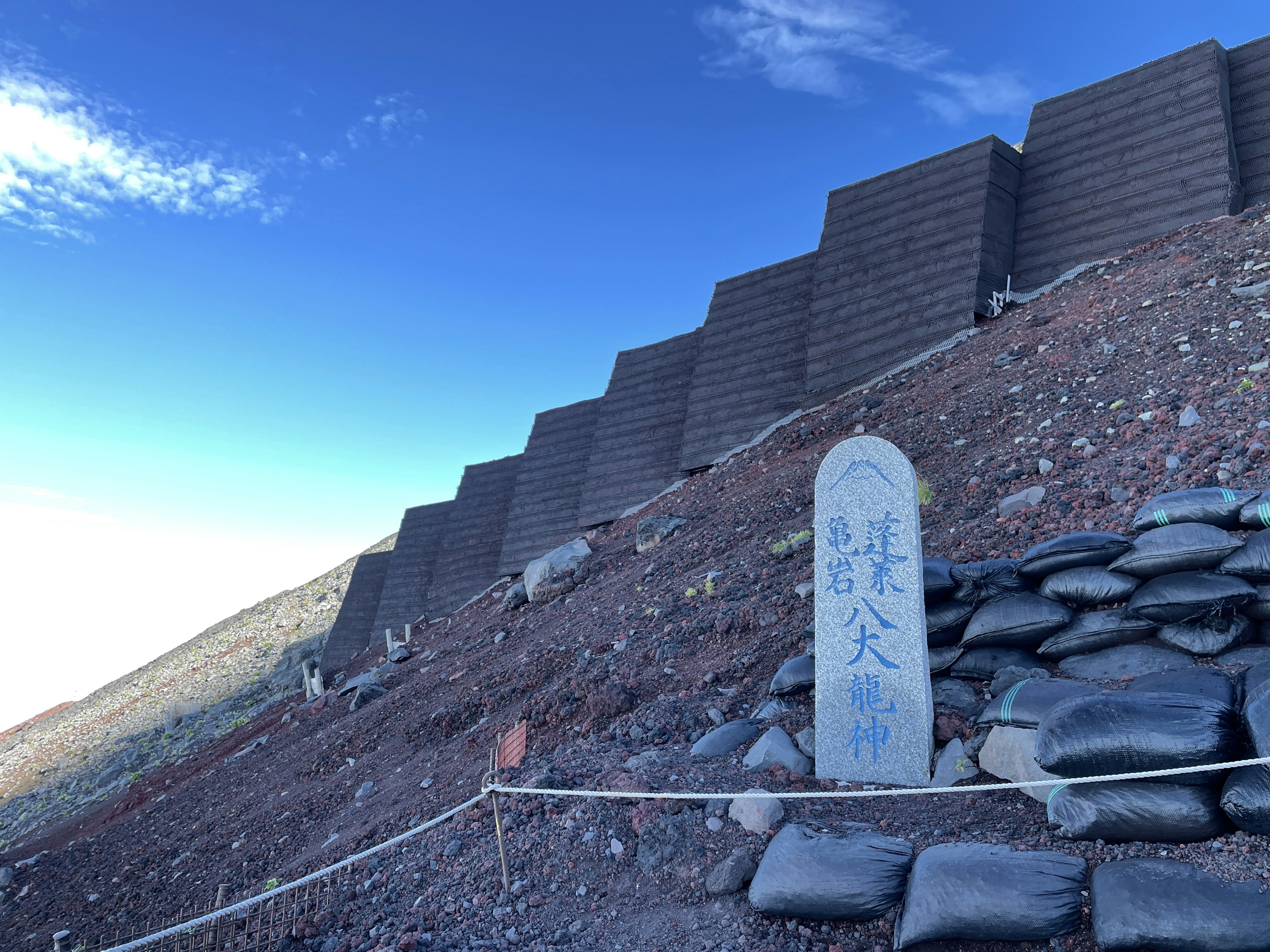 山の斜面にある石碑とコンクリートの壁が見える風景