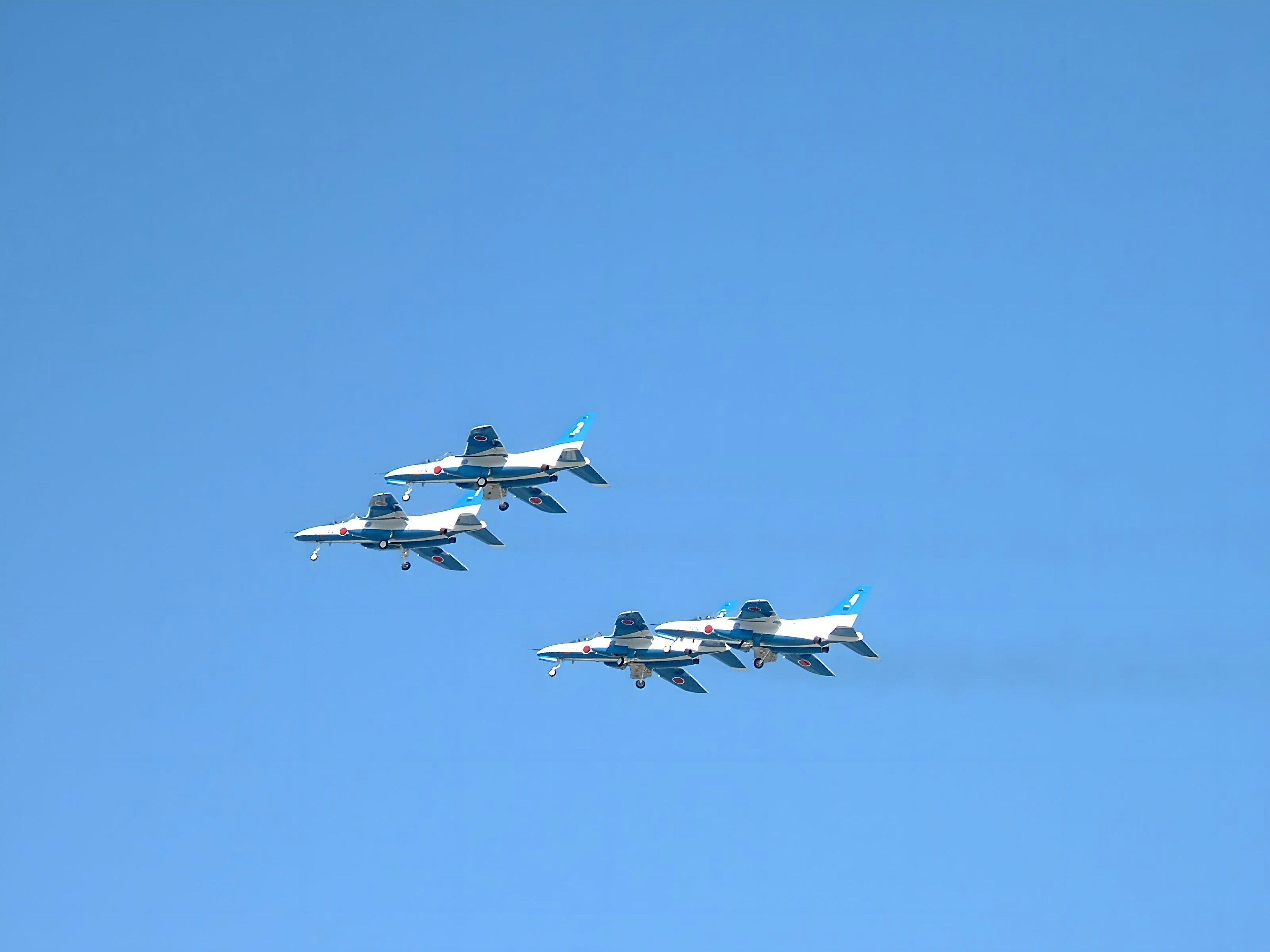 Formazione di quattro aerei da combattimento che volano in un cielo blu chiaro