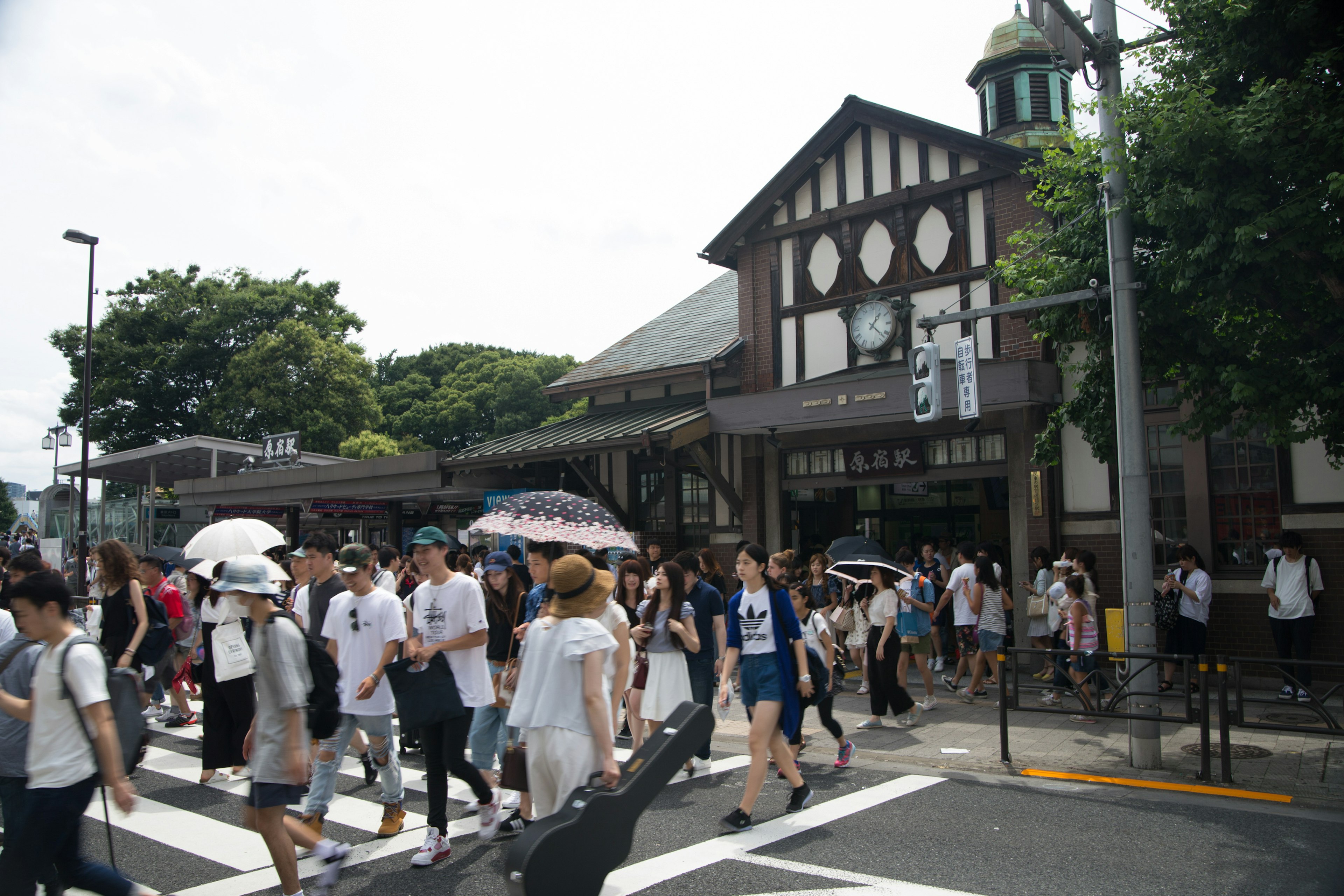 Crowded intersection with people walking and a traditional architecture station