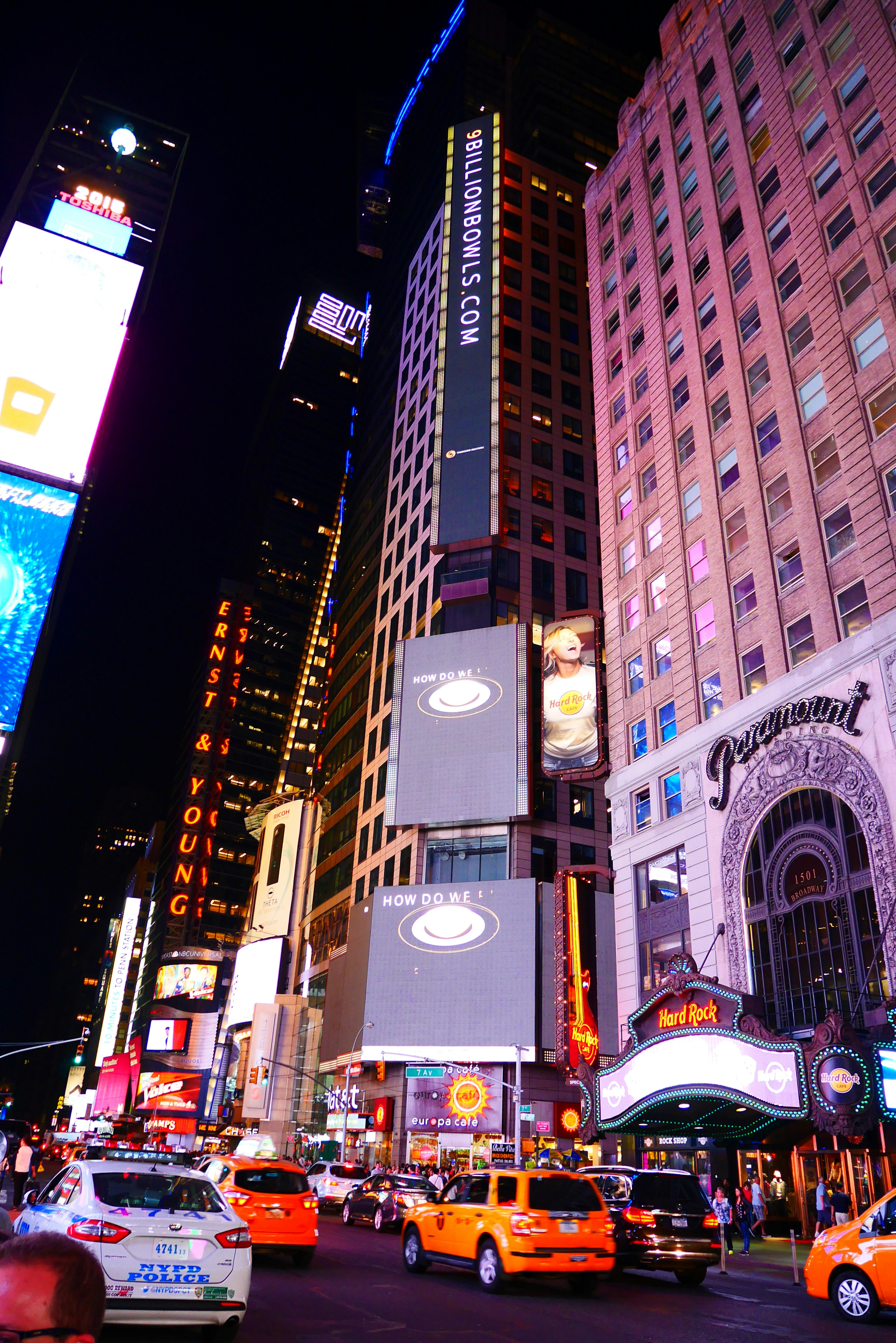 Pemandangan malam Times Square dengan gedung pencakar langit dan taksi kuning