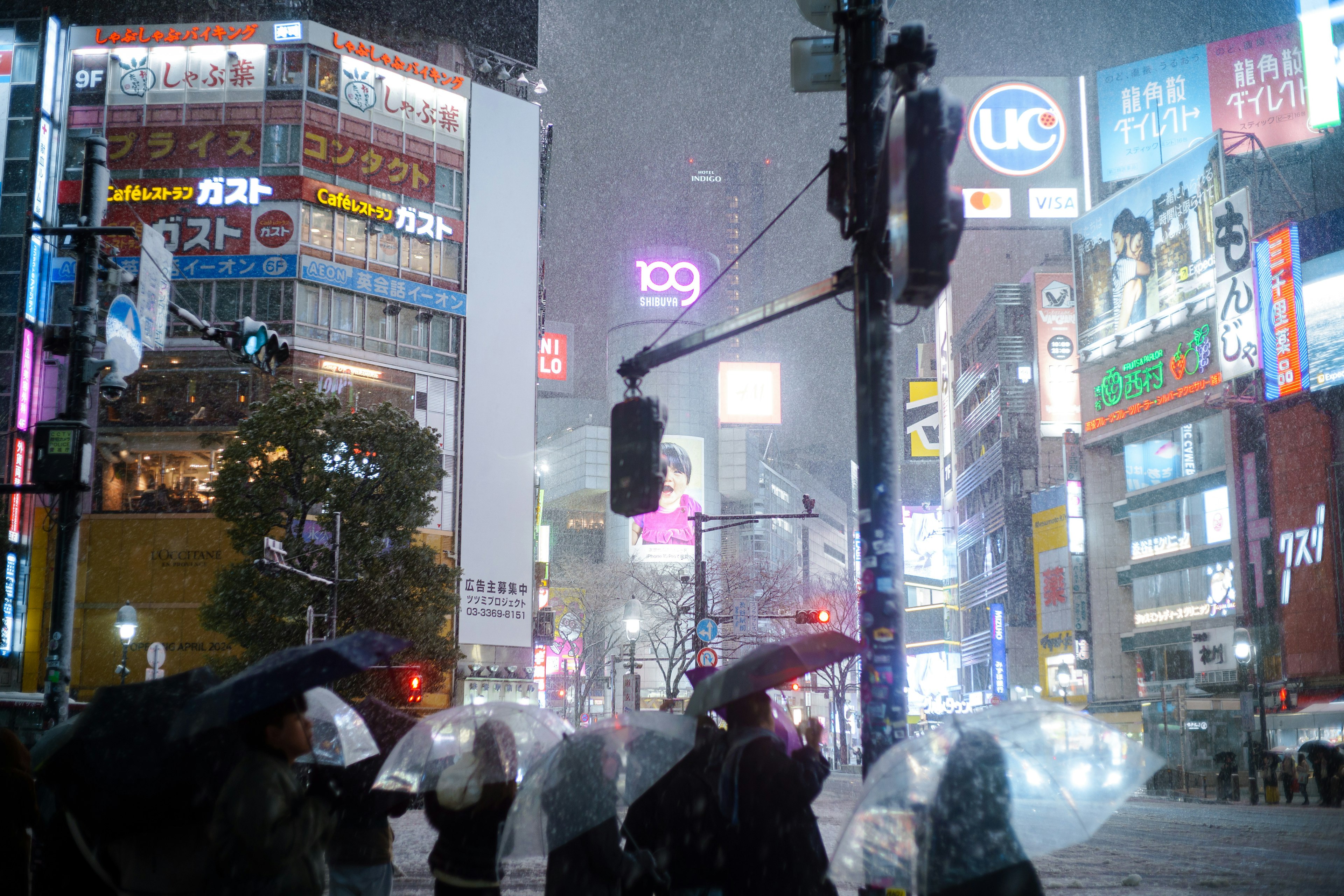 雨の中で傘を持つ人々と輝くネオンサインのある都市の景色