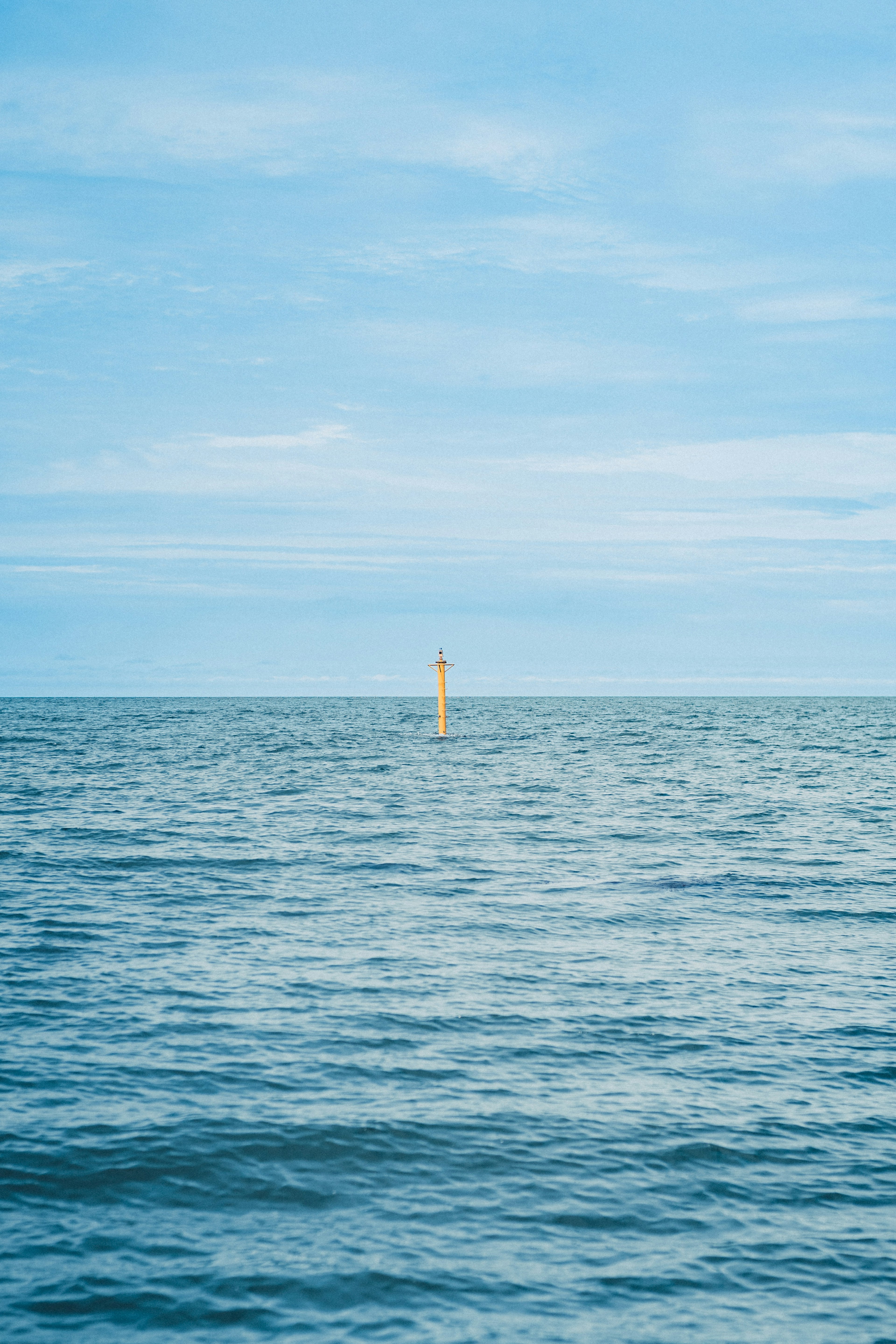 Yellow lighthouse in a blue ocean and sky landscape