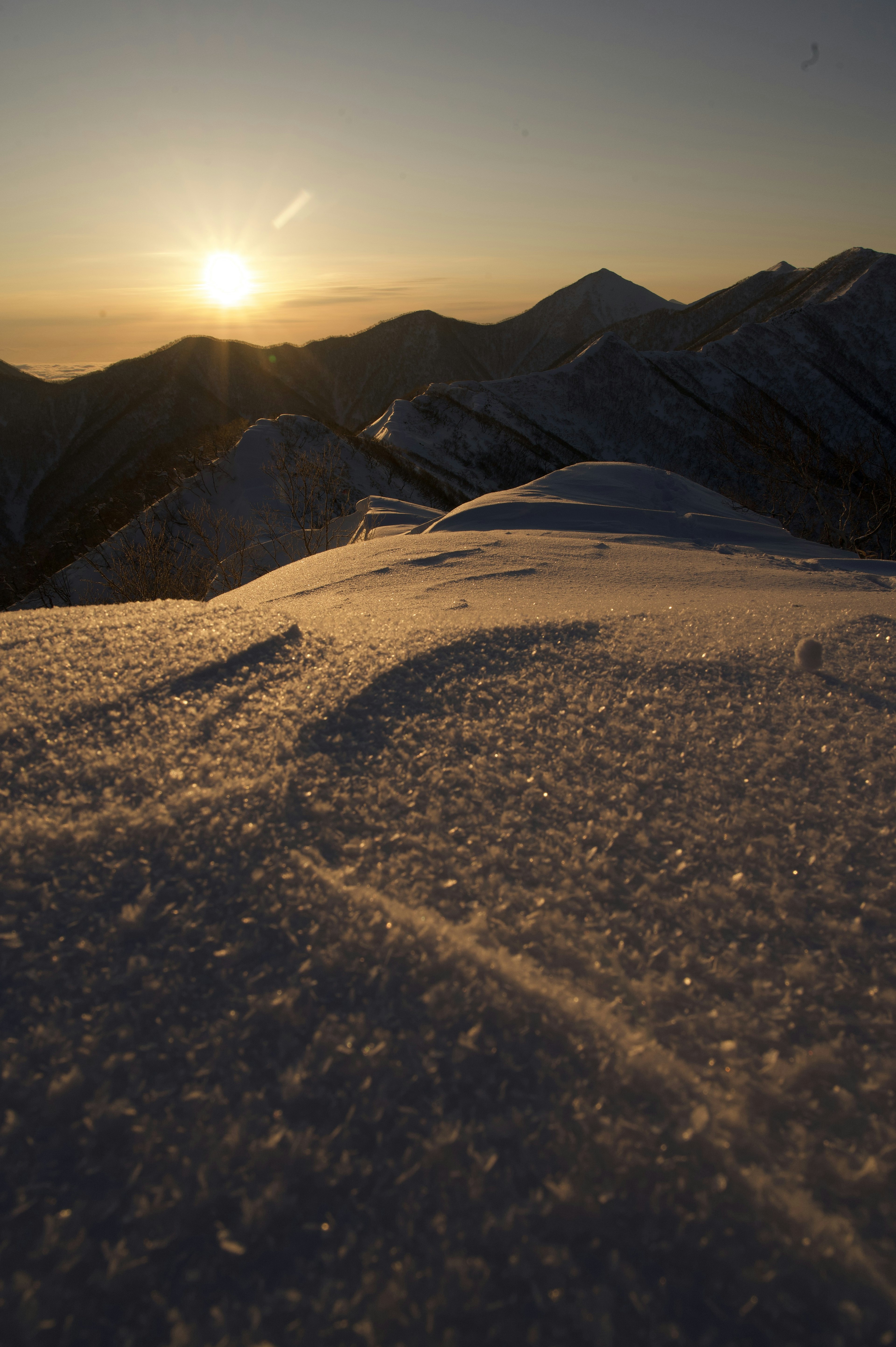 Coucher de soleil sur des sommets de montagne enneigés avec un premier plan de neige scintillante