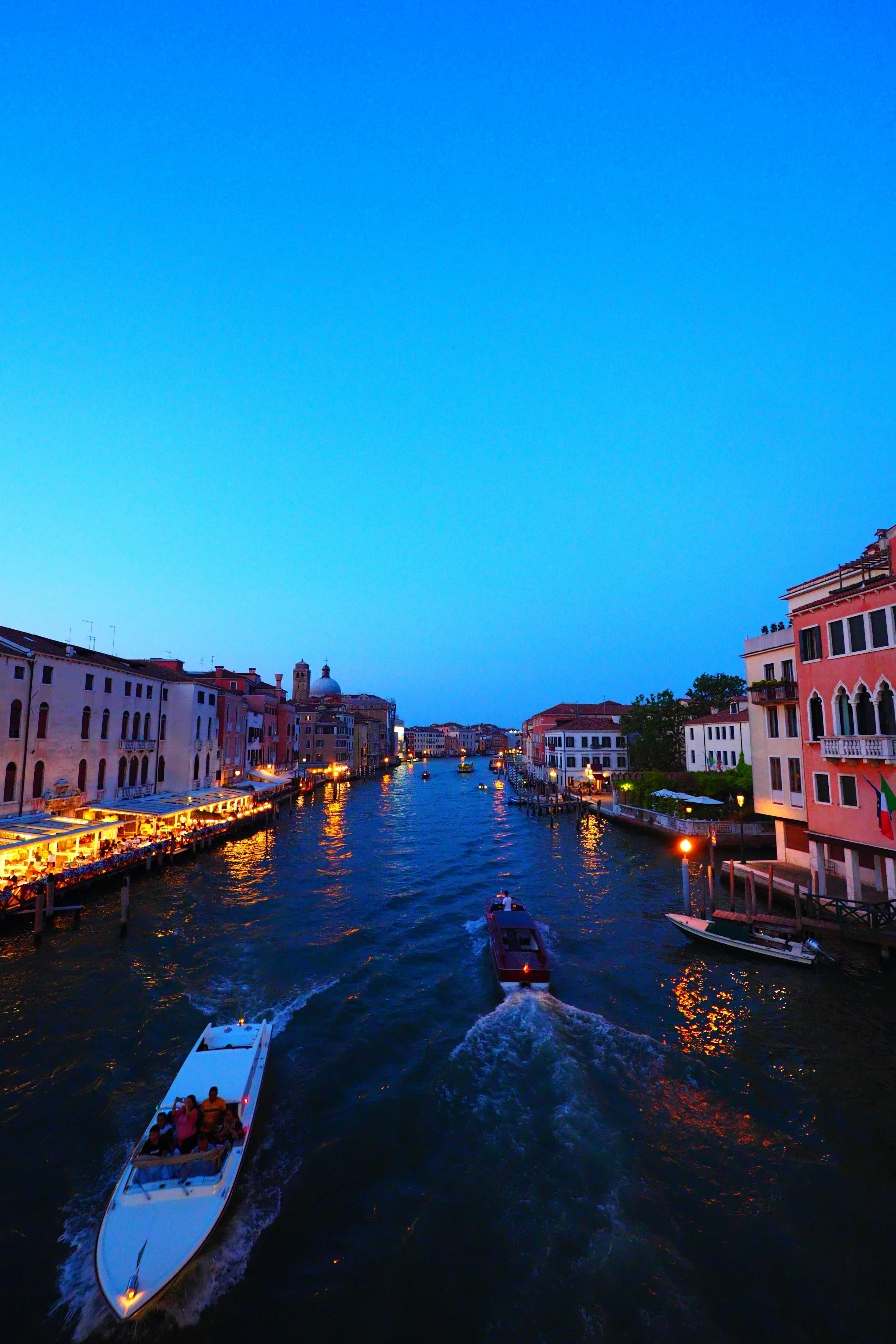 Pemandangan malam Venesia dengan langit biru dan bangunan di sepanjang kanal