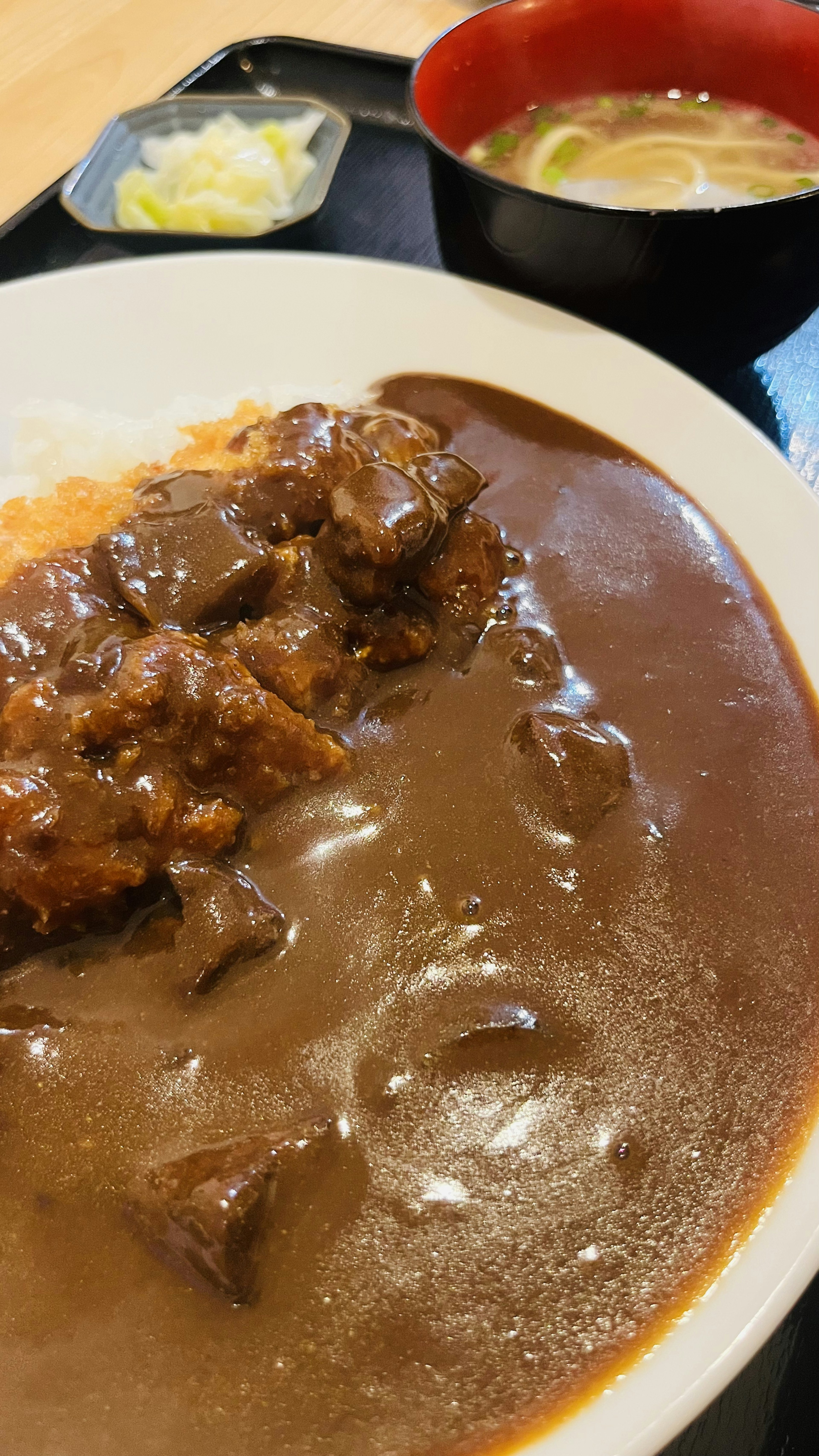 A plate of delicious curry rice featuring rich curry sauce served with rice accompanied by a side of salad and miso soup