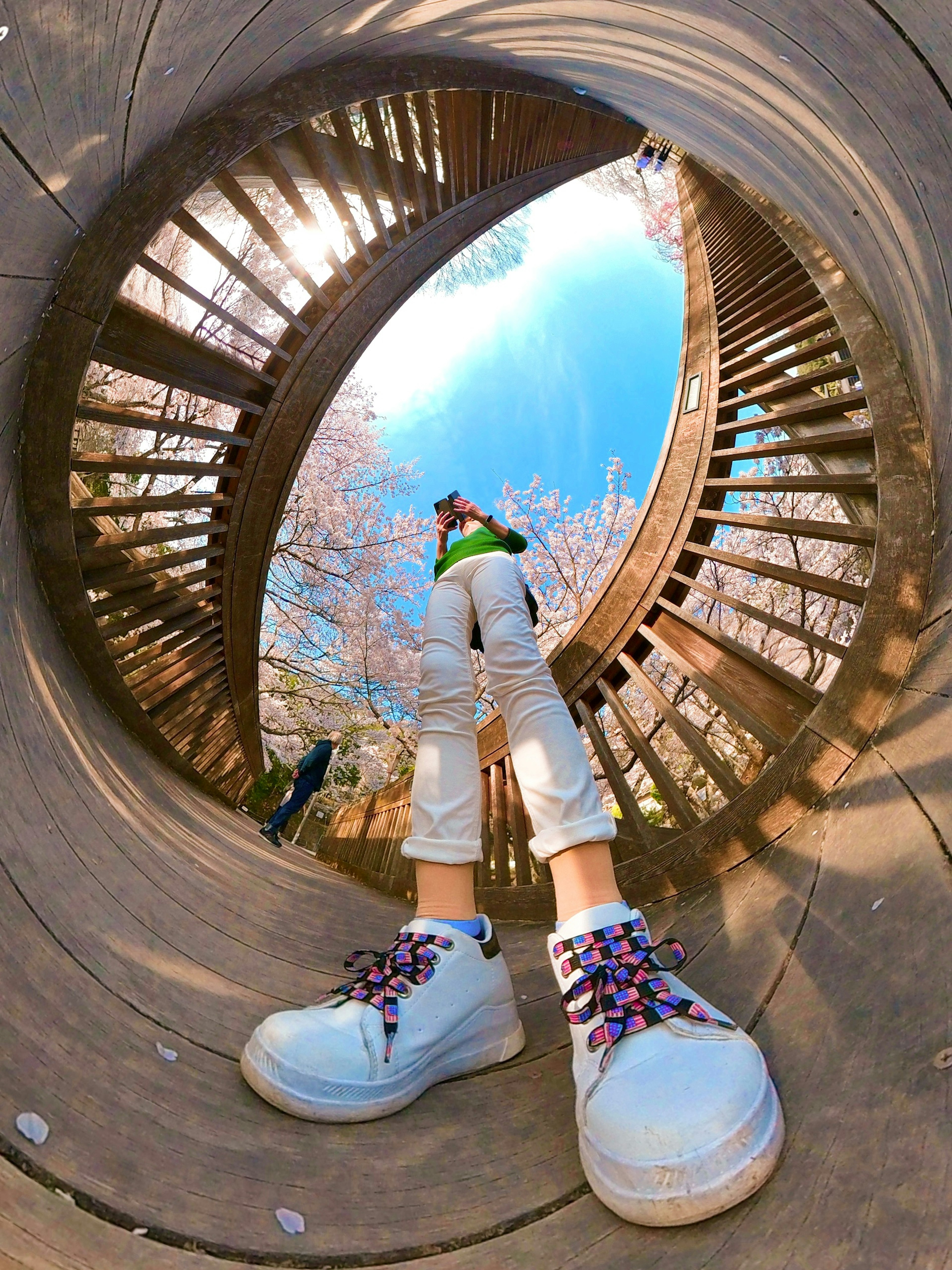 Vue depuis l'intérieur d'un tunnel en bois avec des chaussures blanches et un ciel bleu