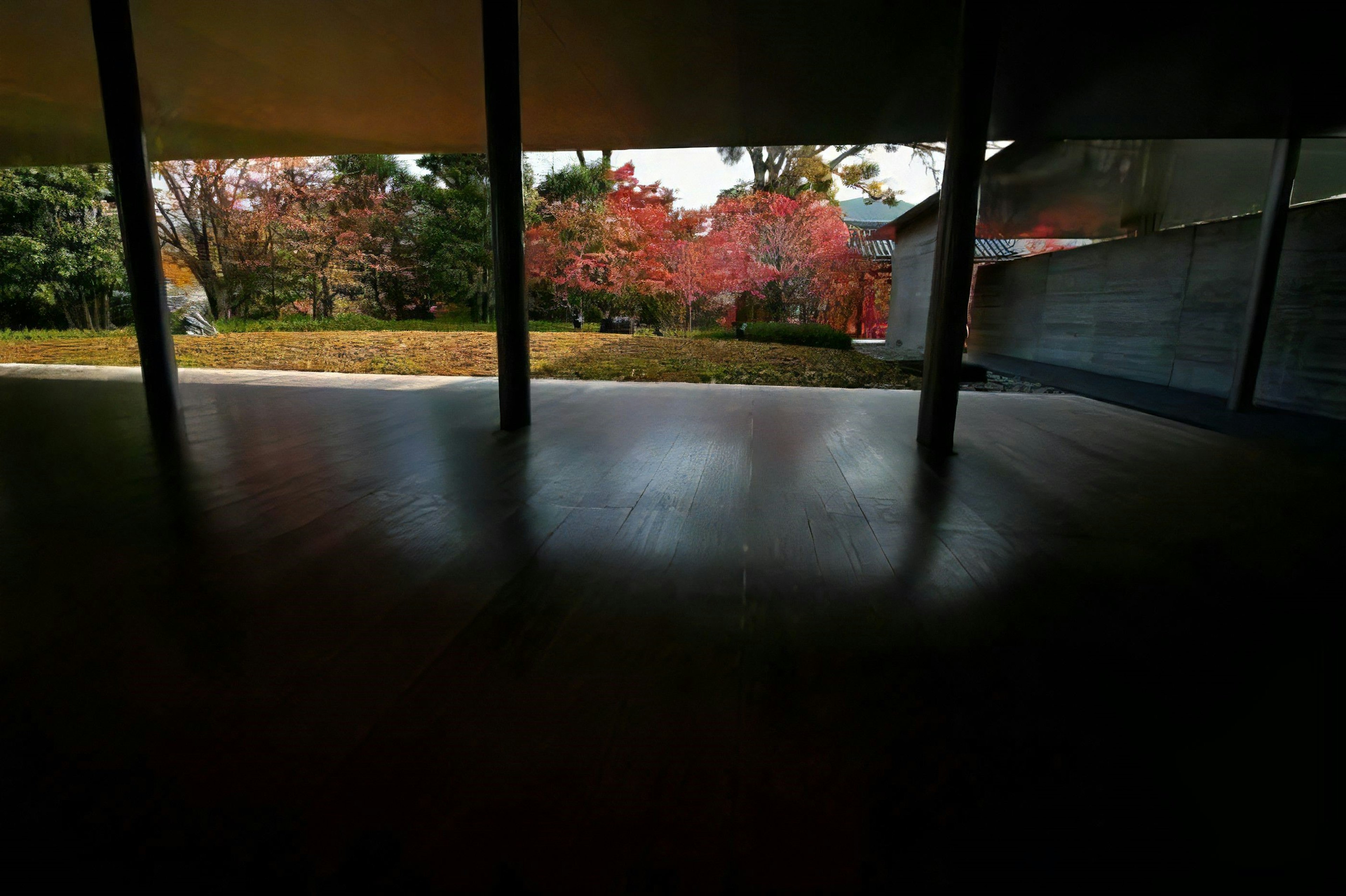 Vista interior que muestra un jardín con un follaje rojo vibrante visible a través de grandes ventanas