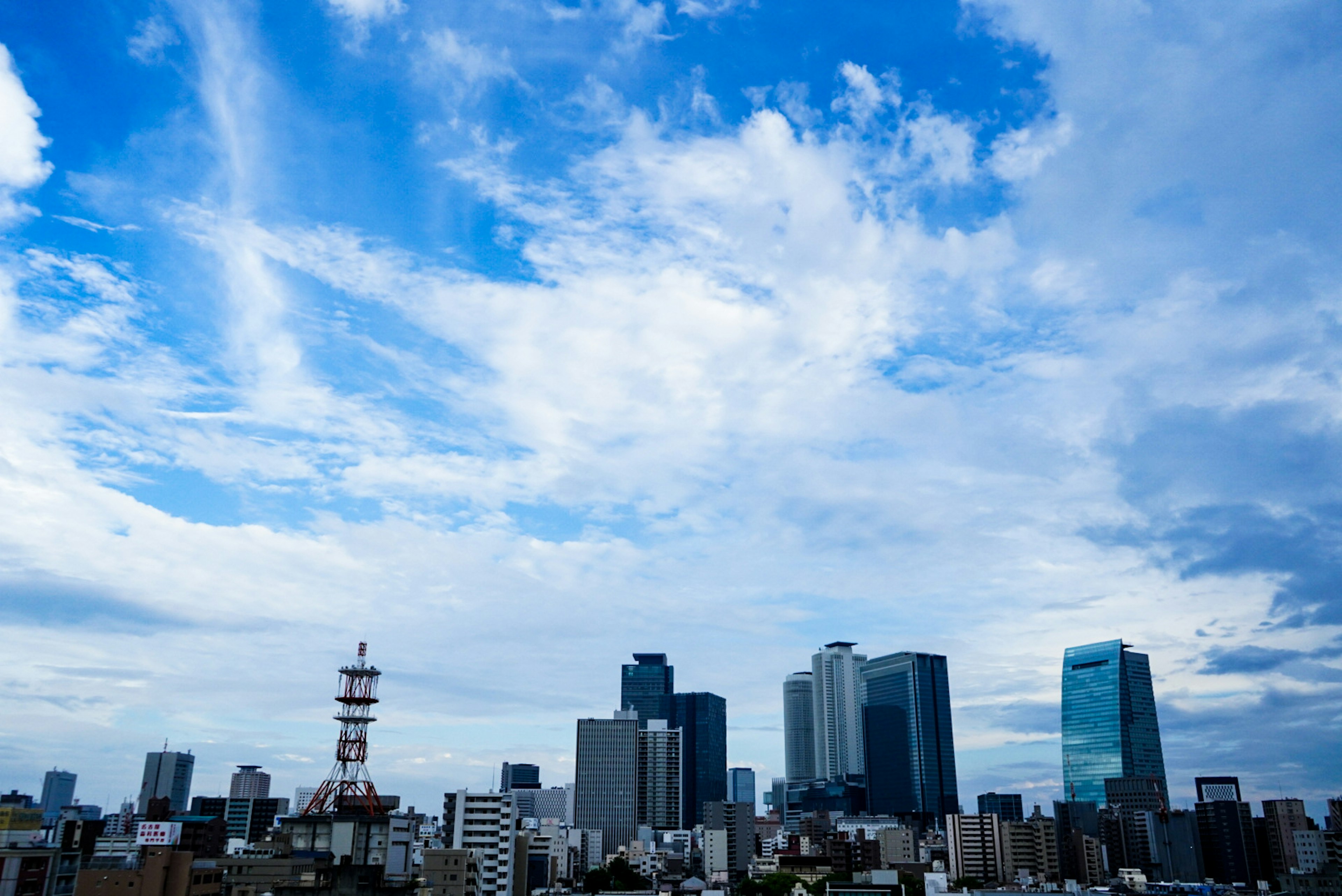 青空と雲が広がる東京の高層ビル群の風景