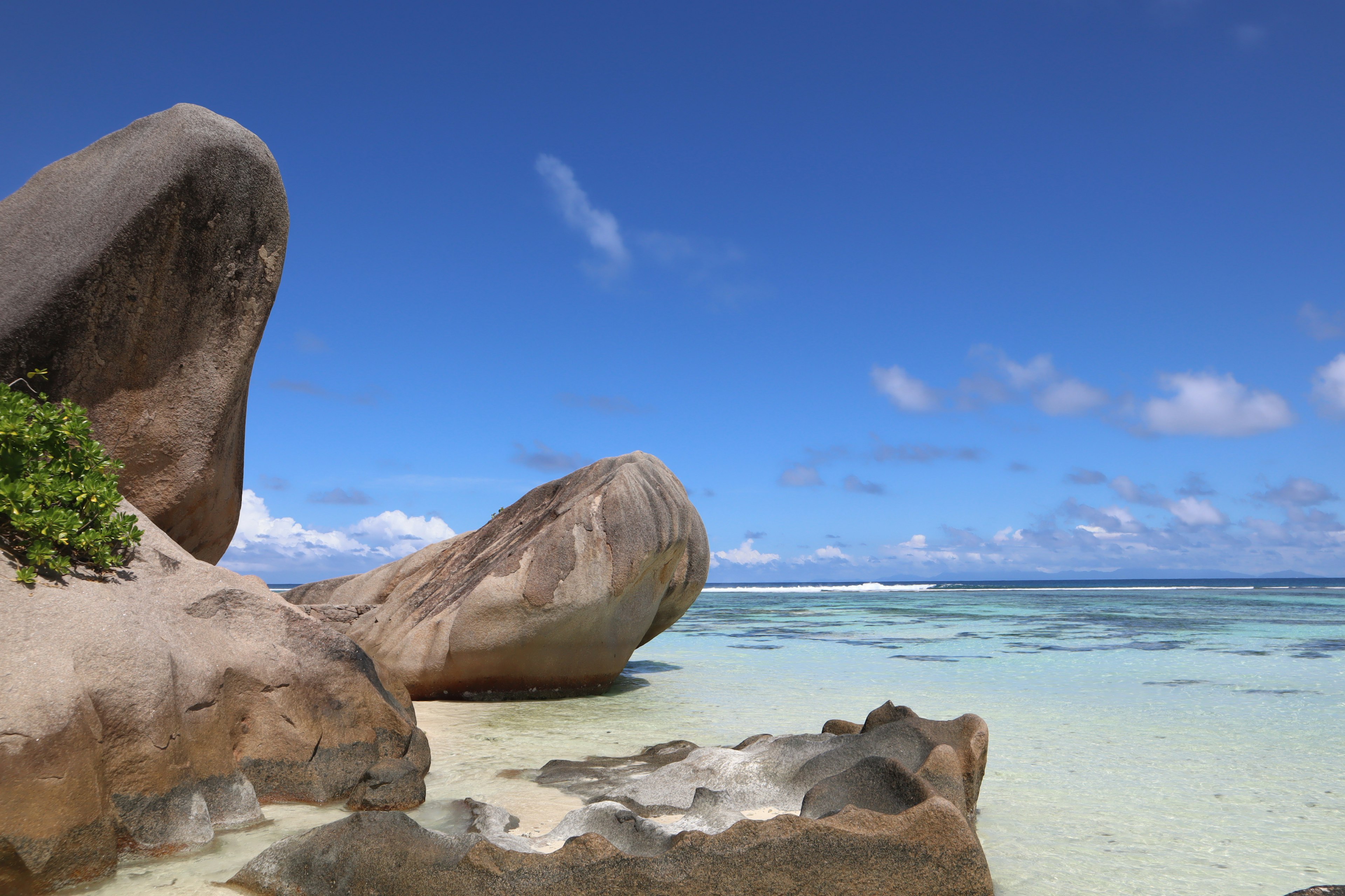 ทิวทัศน์ชายหาดที่สวยงาม มีหินขนาดใหญ่และท้องฟ้าสีฟ้า