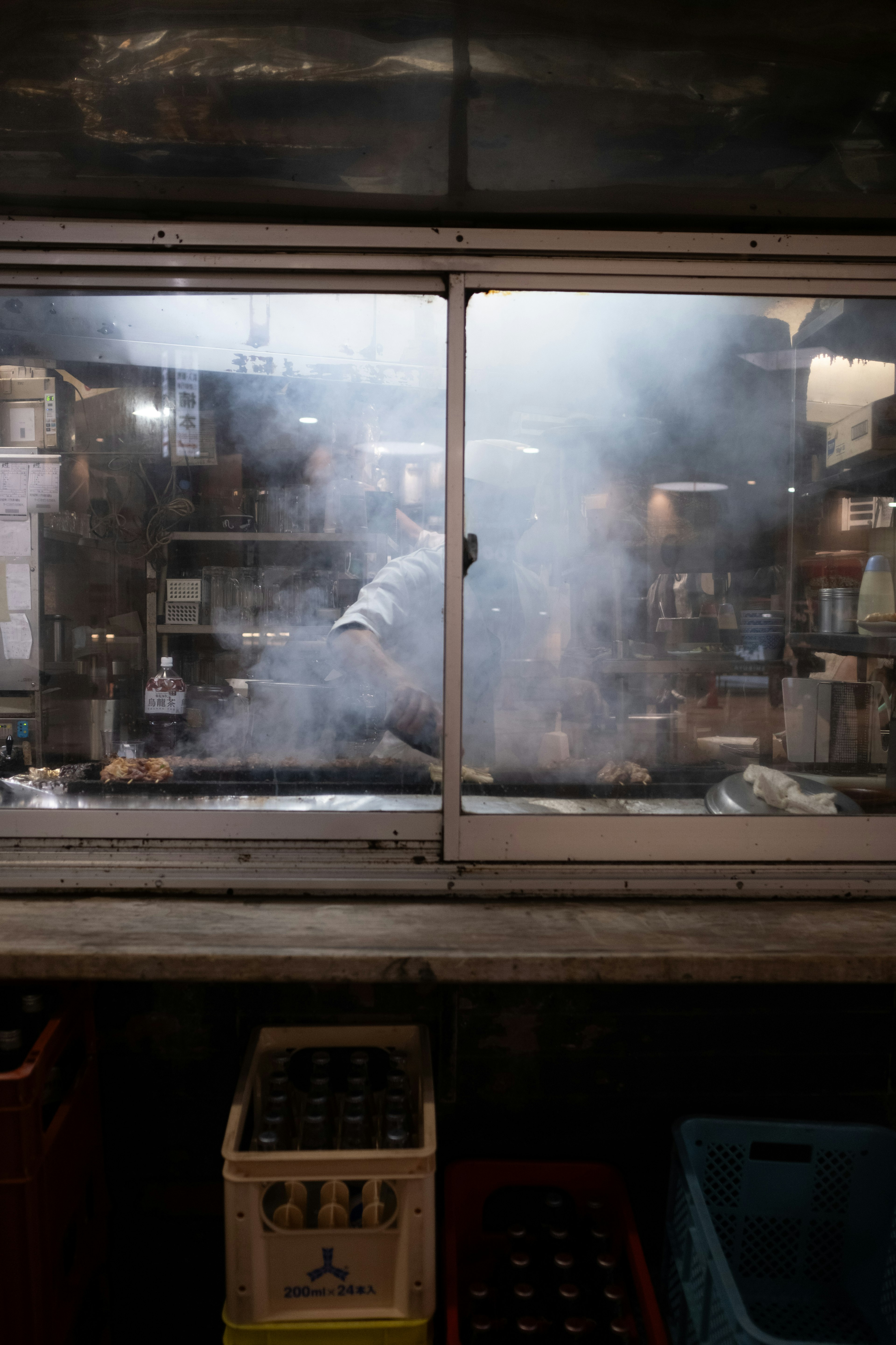 Cuoco che cucina in una cucina piena di fumo vista attraverso una finestra