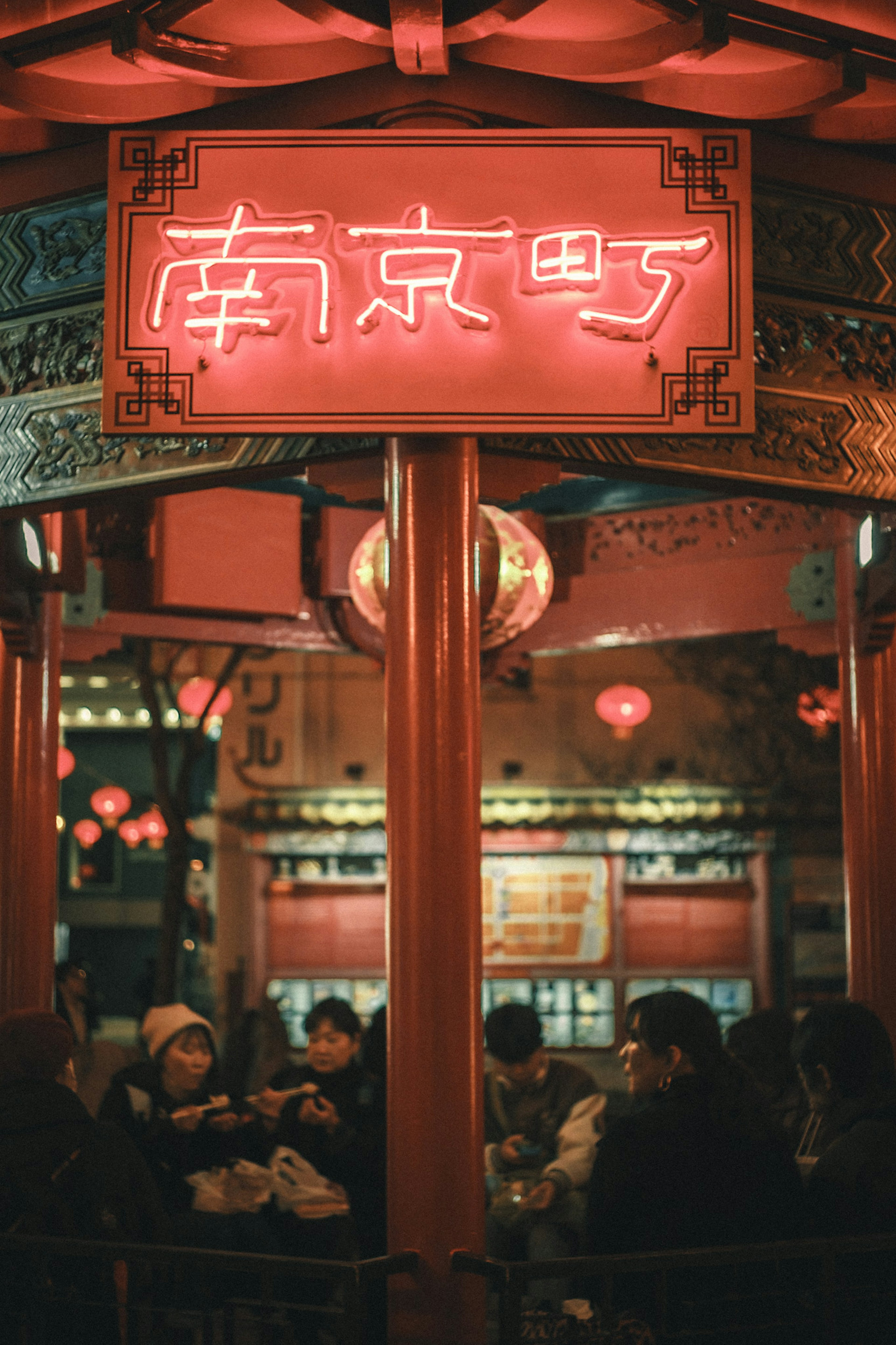 Beleuchtetes rotes Schild der Nanjing Street mit Menschen, die sich in einer lebhaften Szene versammeln