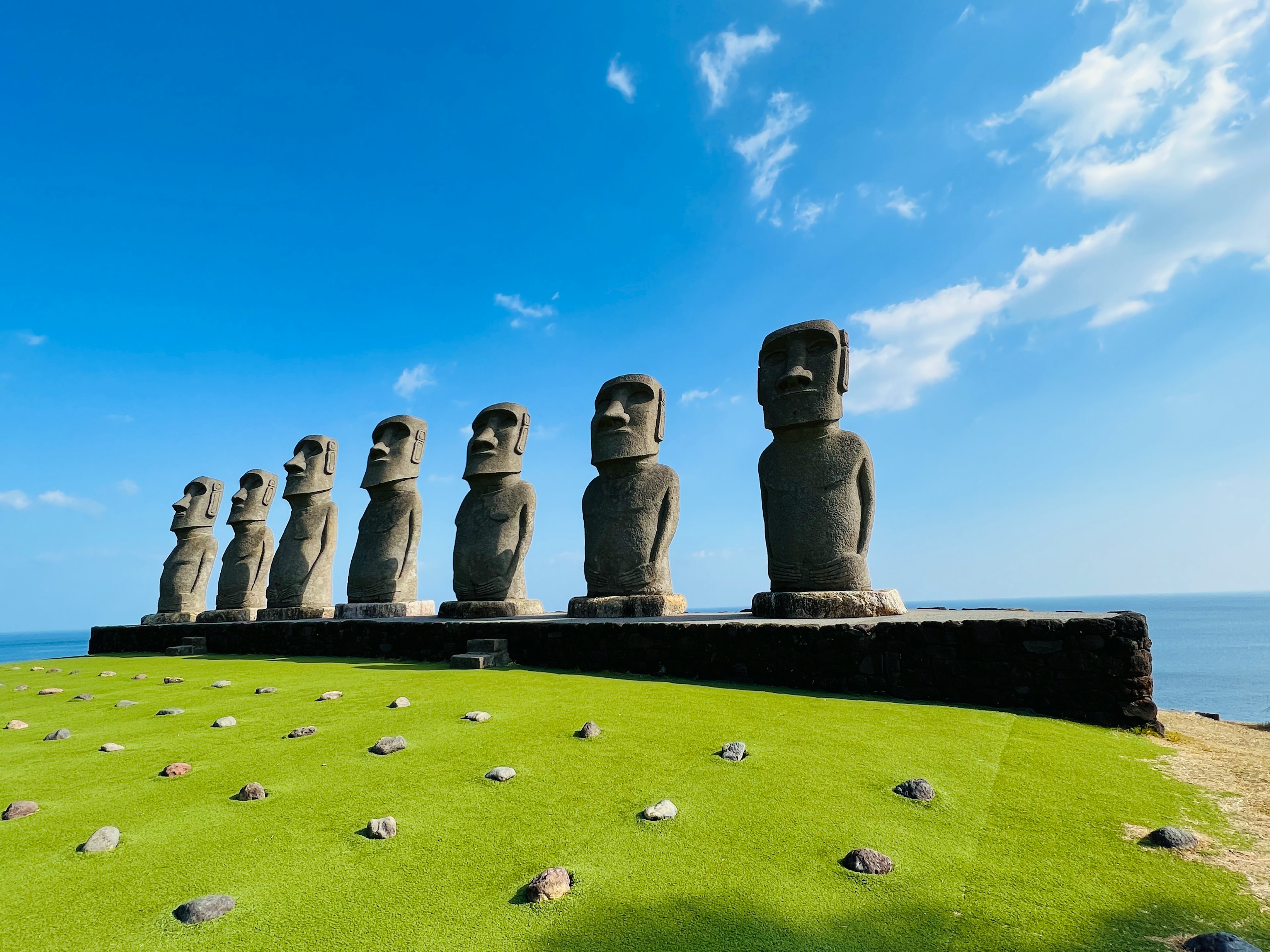 Barisan patung Moai di Pulau Paskah dengan langit biru dan lautan