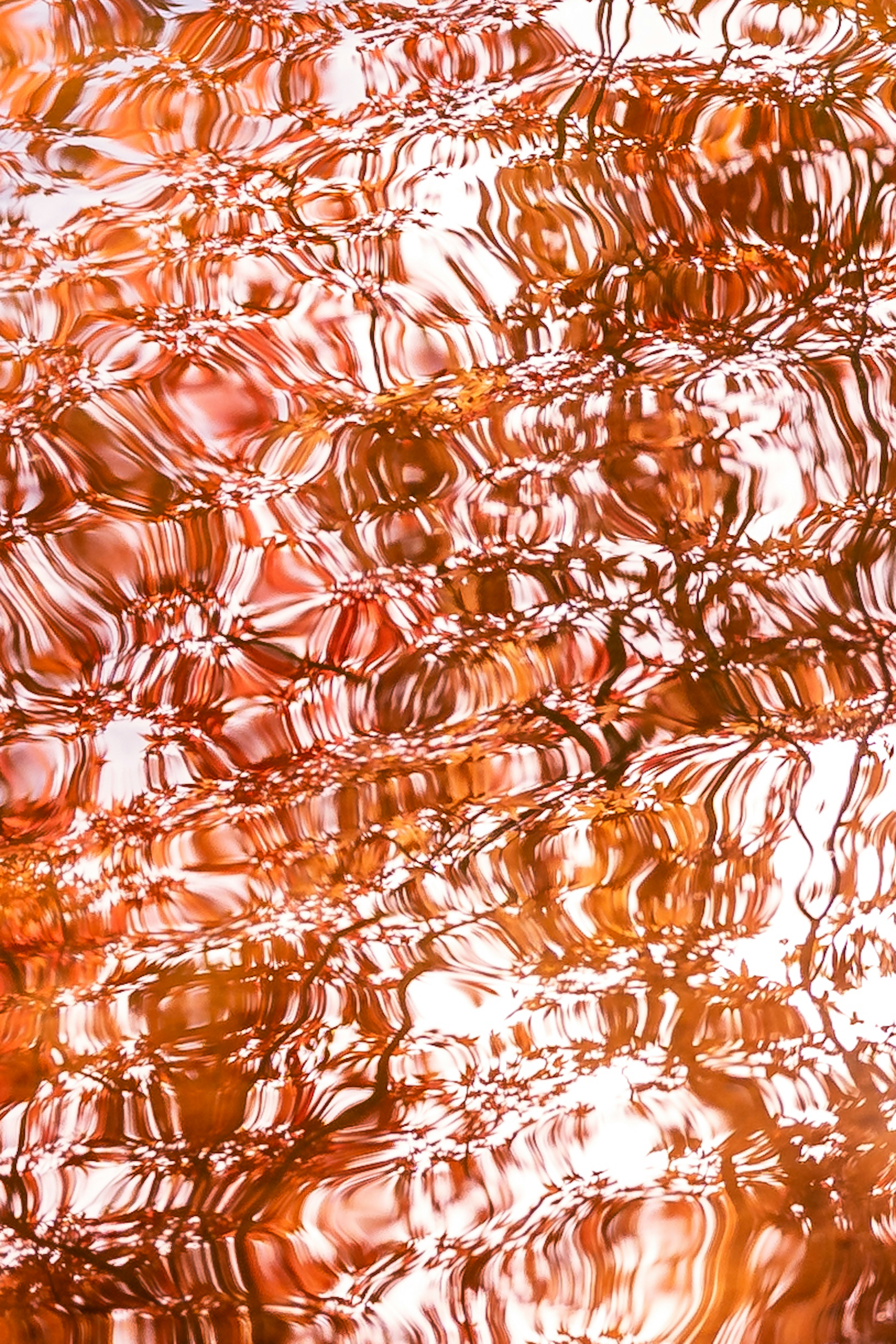 Abstract pattern of orange ripples reflected on water surface