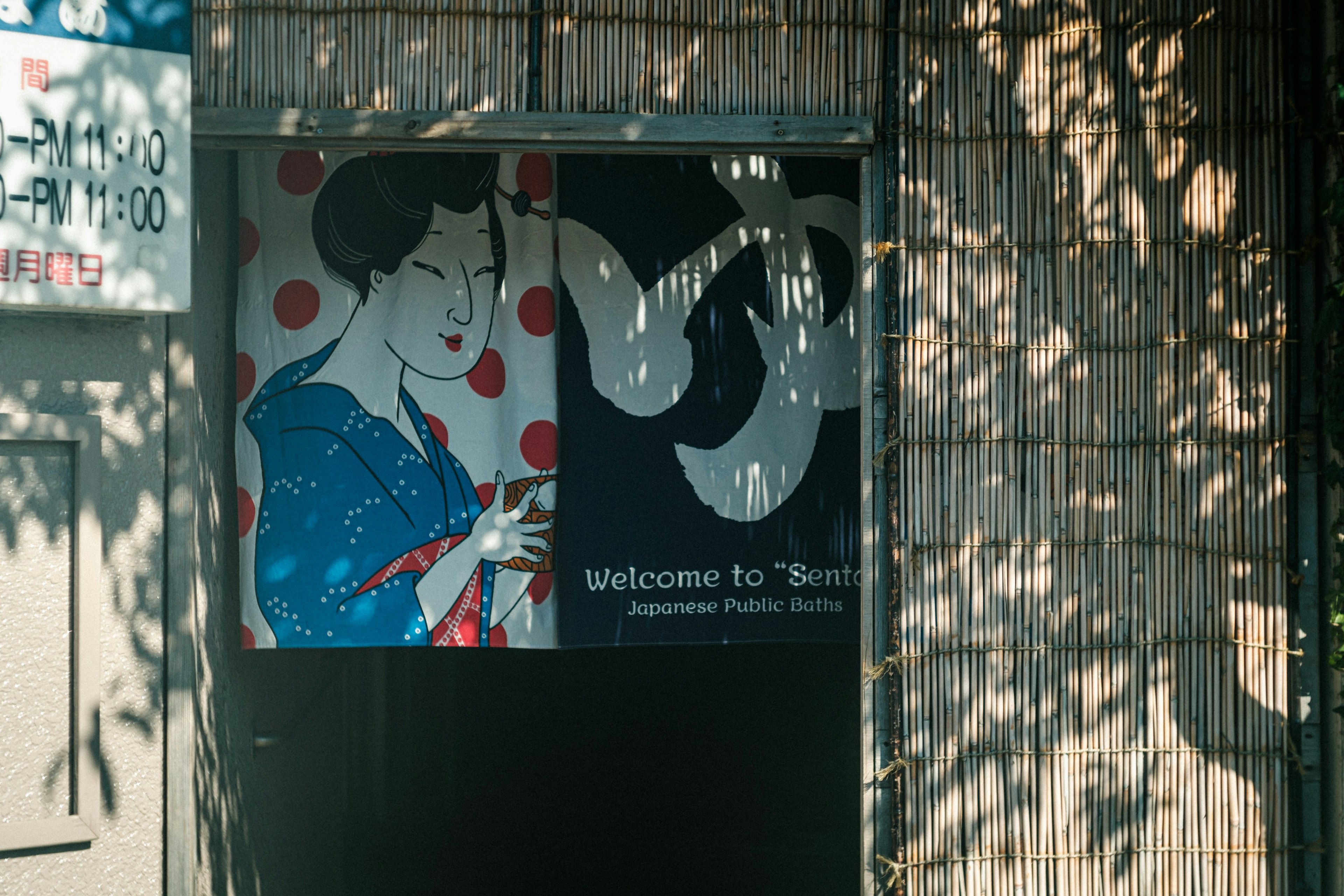 Façade de magasin avec une illustration d'une femme en kimono bleu à pois rouges et une enseigne indiquant Bienvenue à Tofu