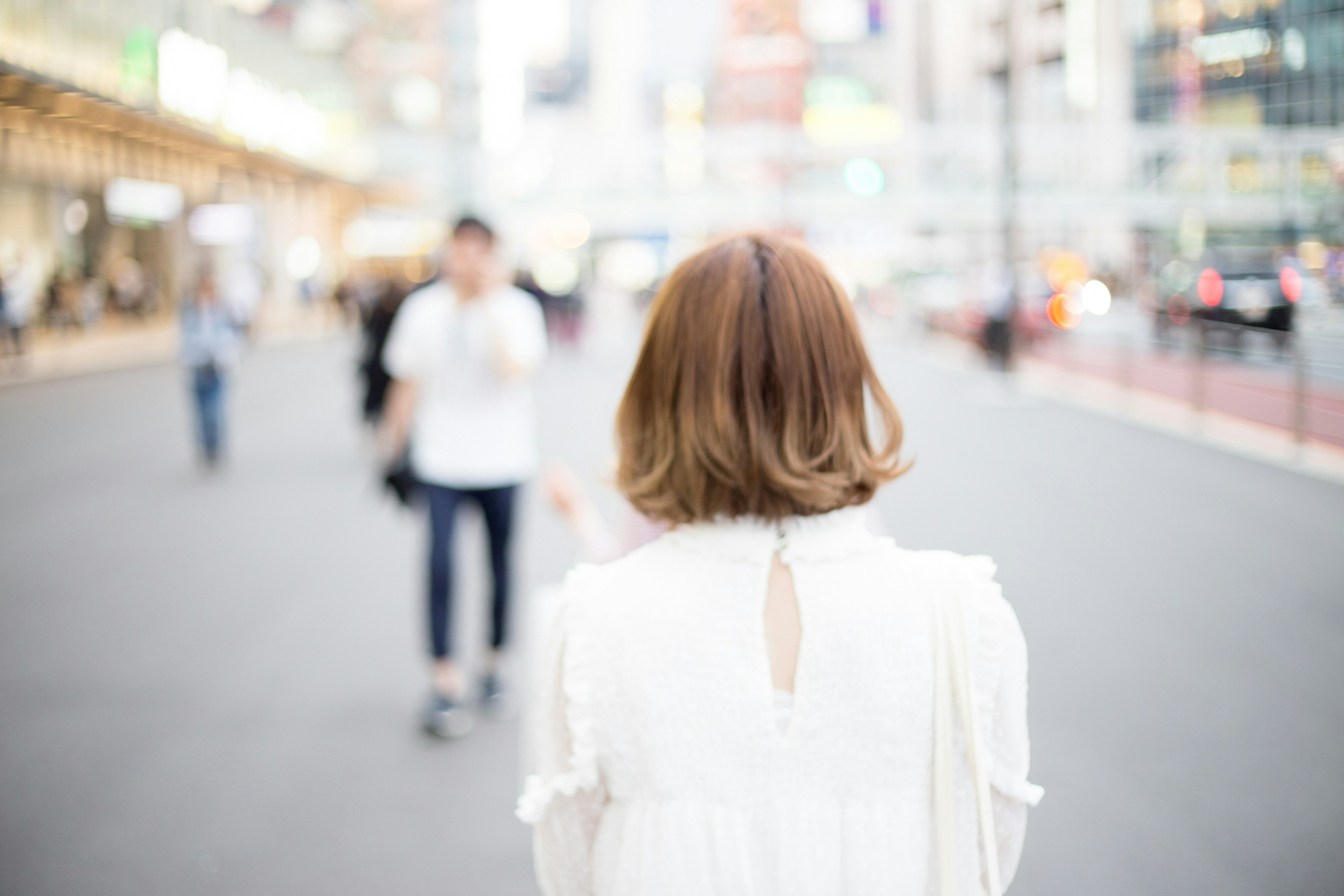 Femme en vêtements blancs vue de dos dans un environnement urbain animé