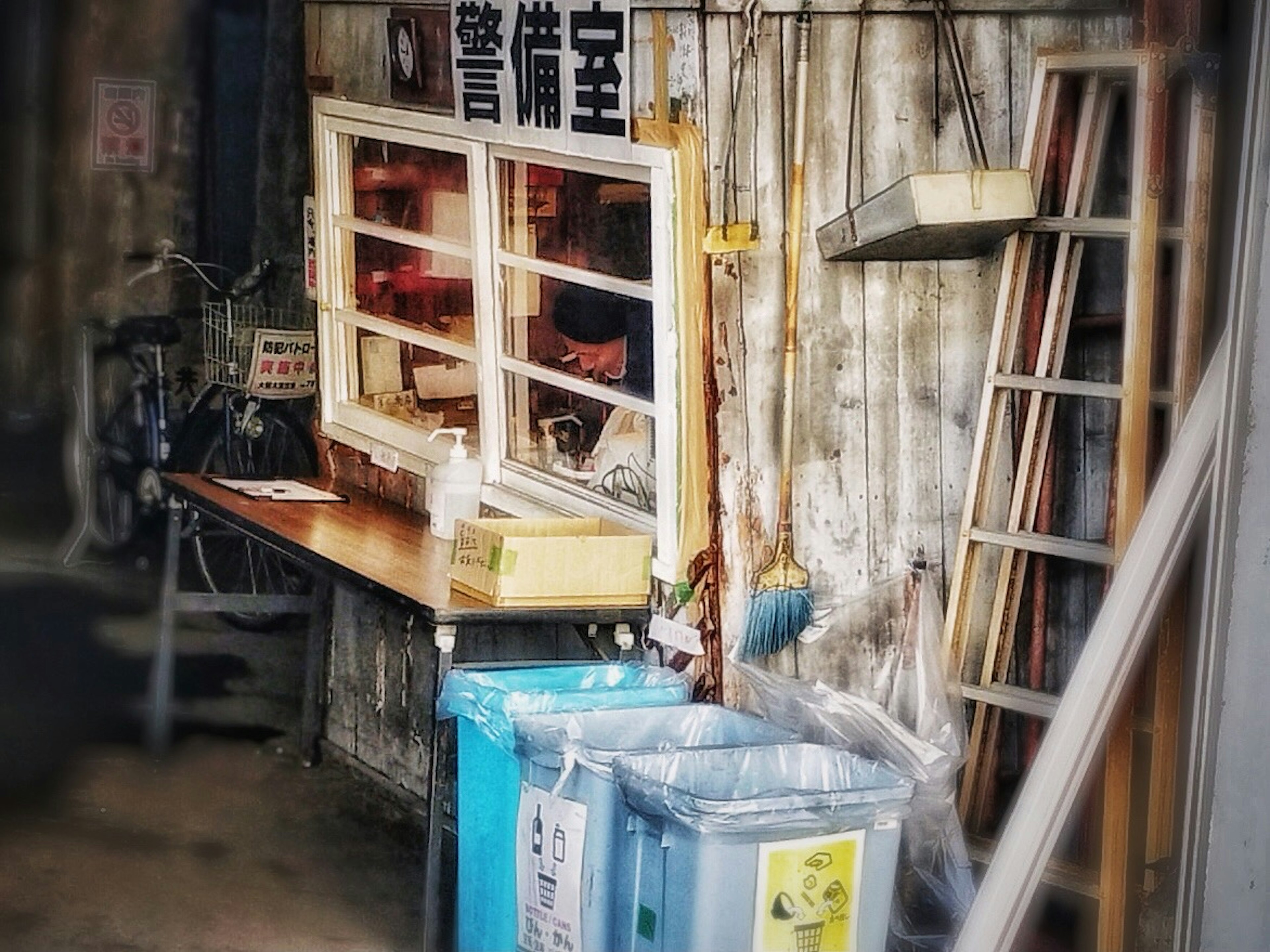 A window counter in an old building with a wooden table and trash bins