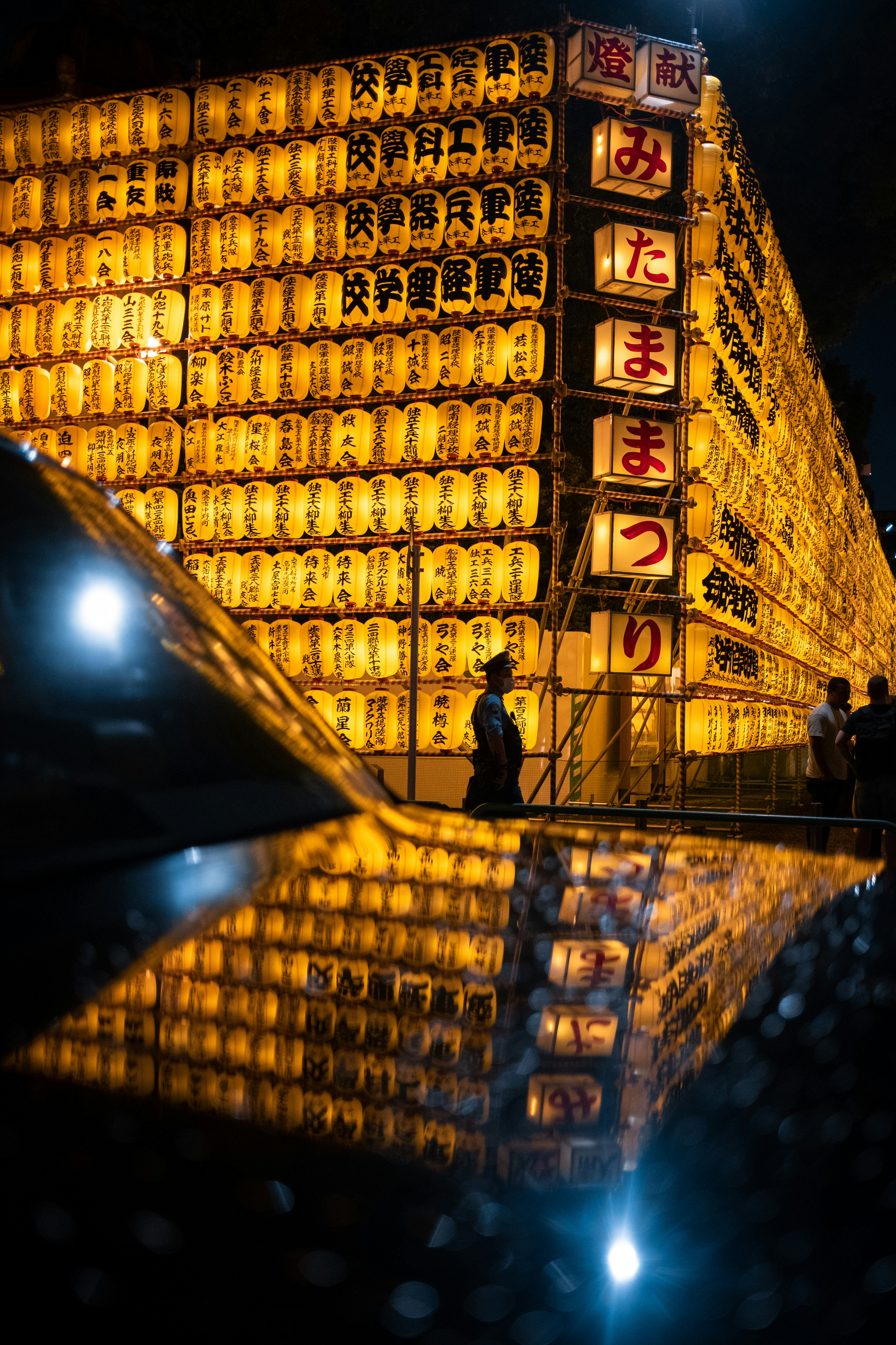 Scène de festival nocturne avec des lanternes illuminées se reflétant au sol