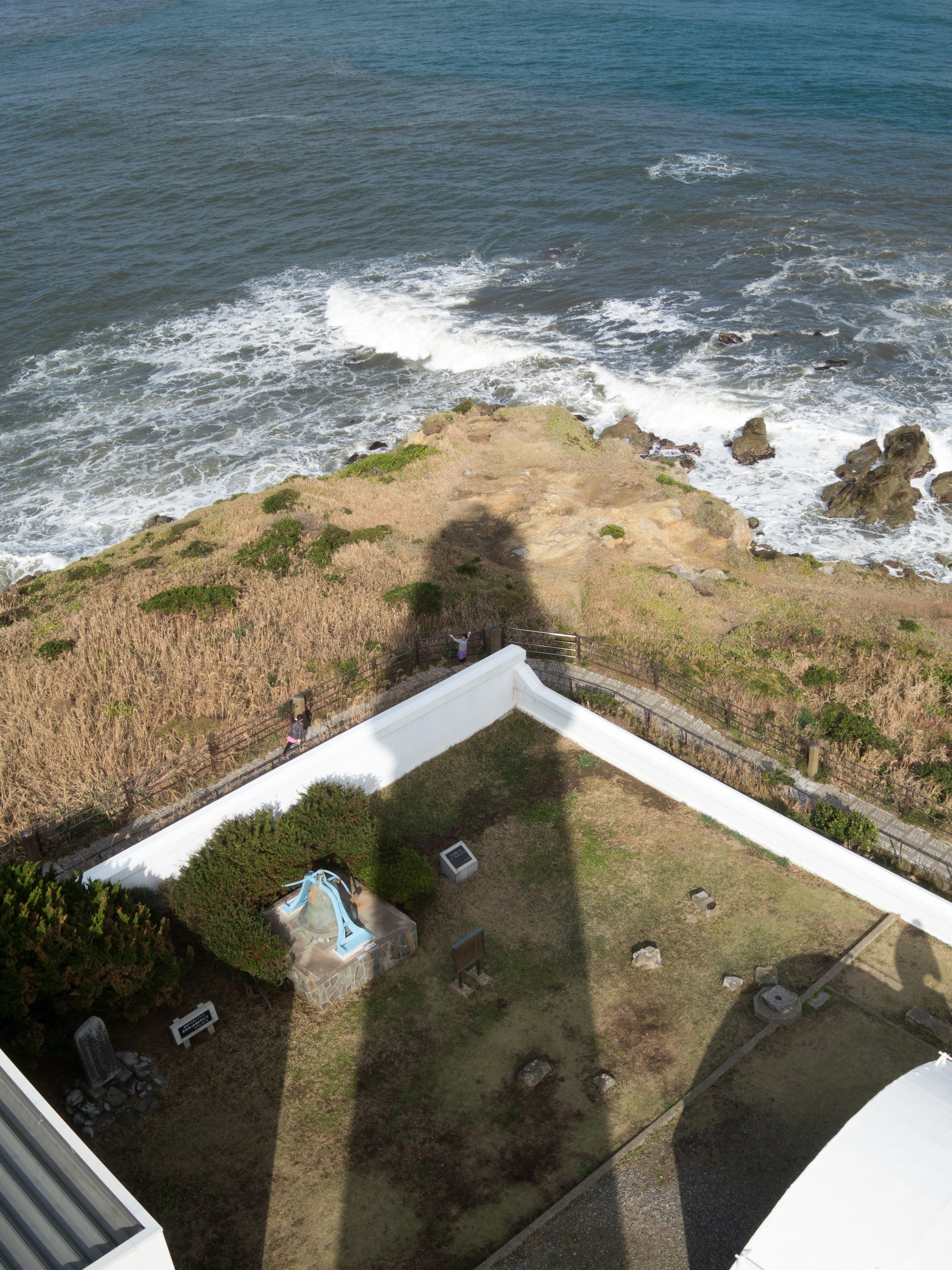 Shadow of a lighthouse extending over the coastal landscape