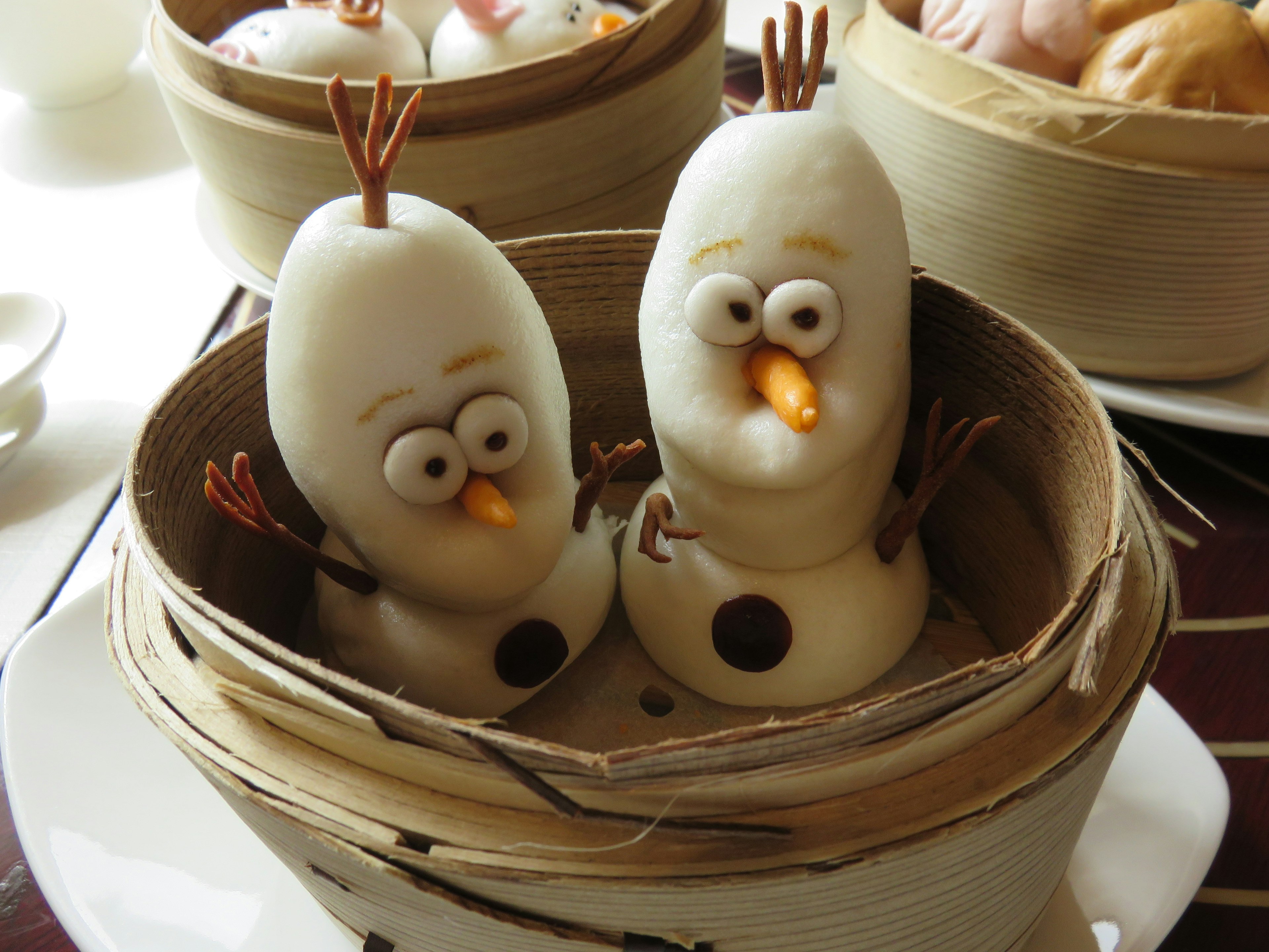 Cute Olaf-shaped steamed buns arranged in a bamboo basket