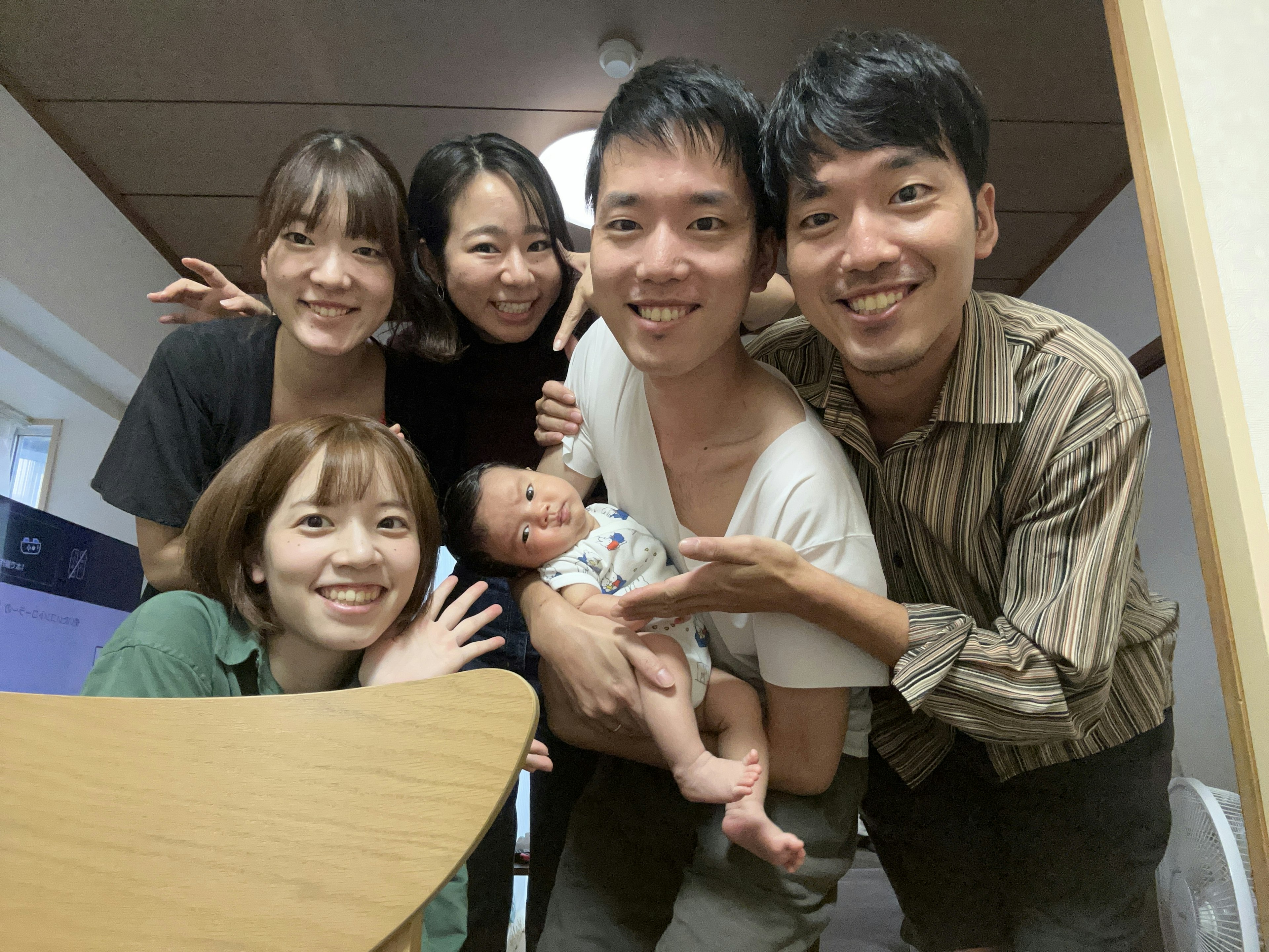 Una foto di famiglia con giovani uomini e donne sorridenti che tengono un bambino