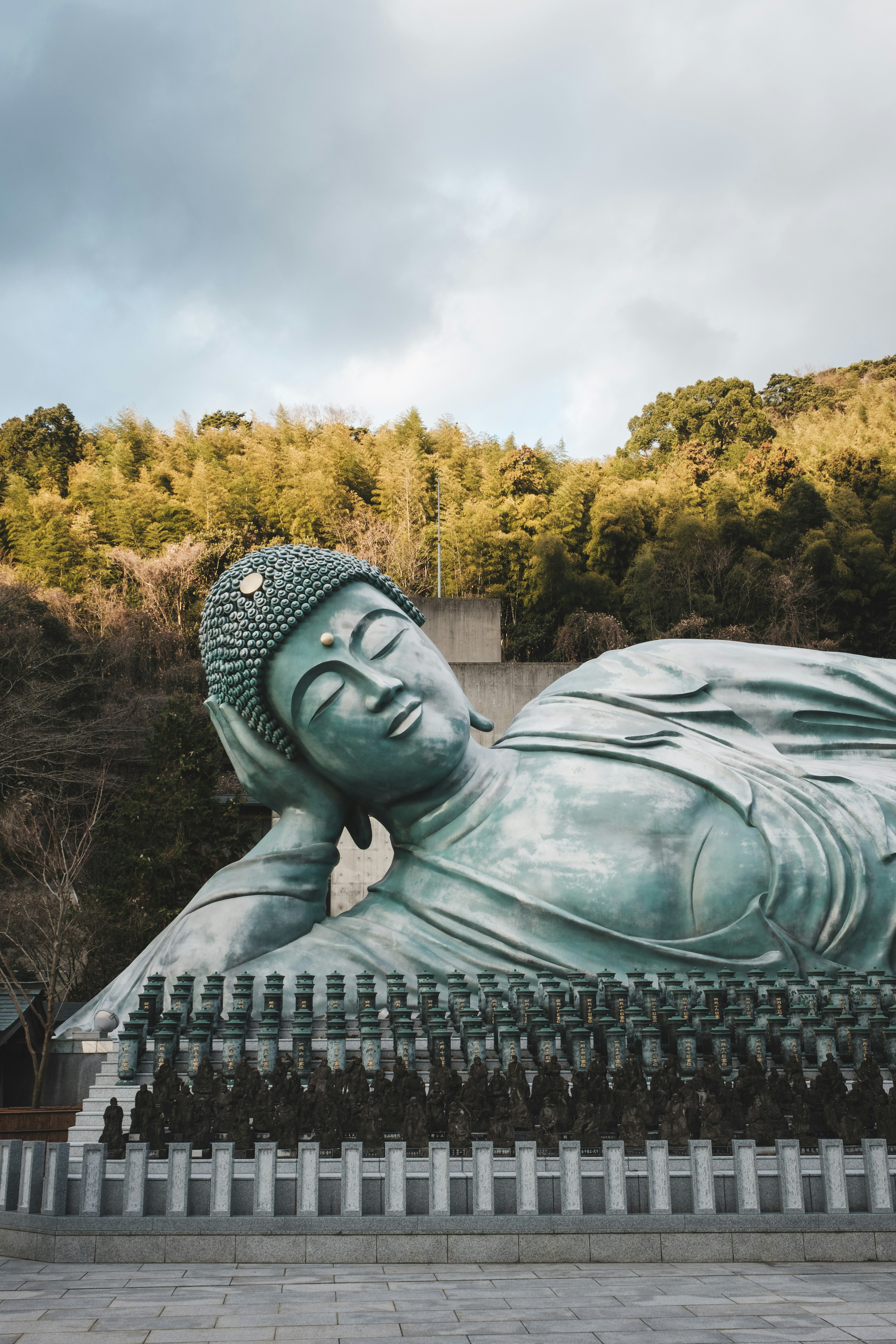 Statue du Bouddha couché entourée de verdure et d'un ciel serein