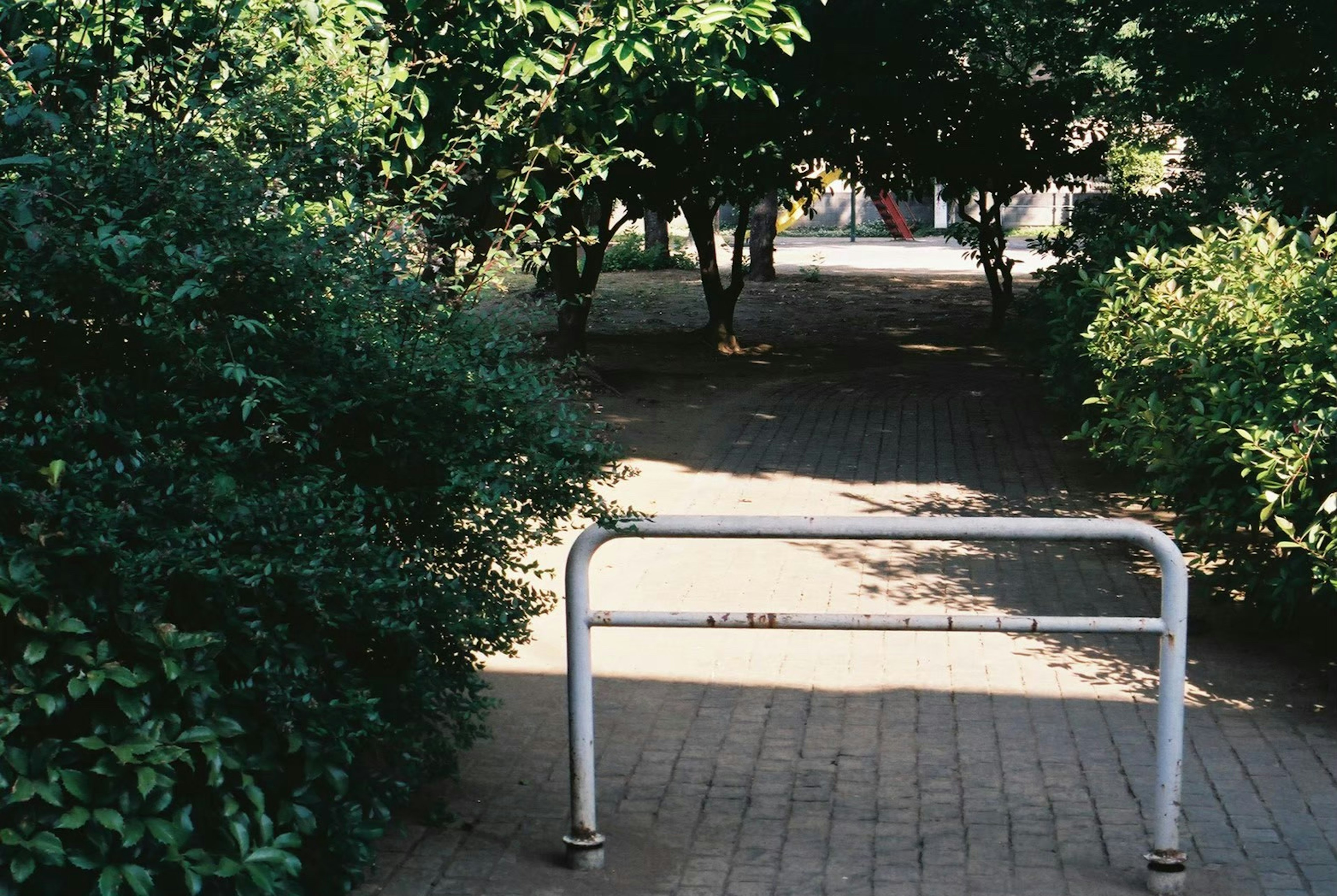 A white barrier at the entrance of a green pathway