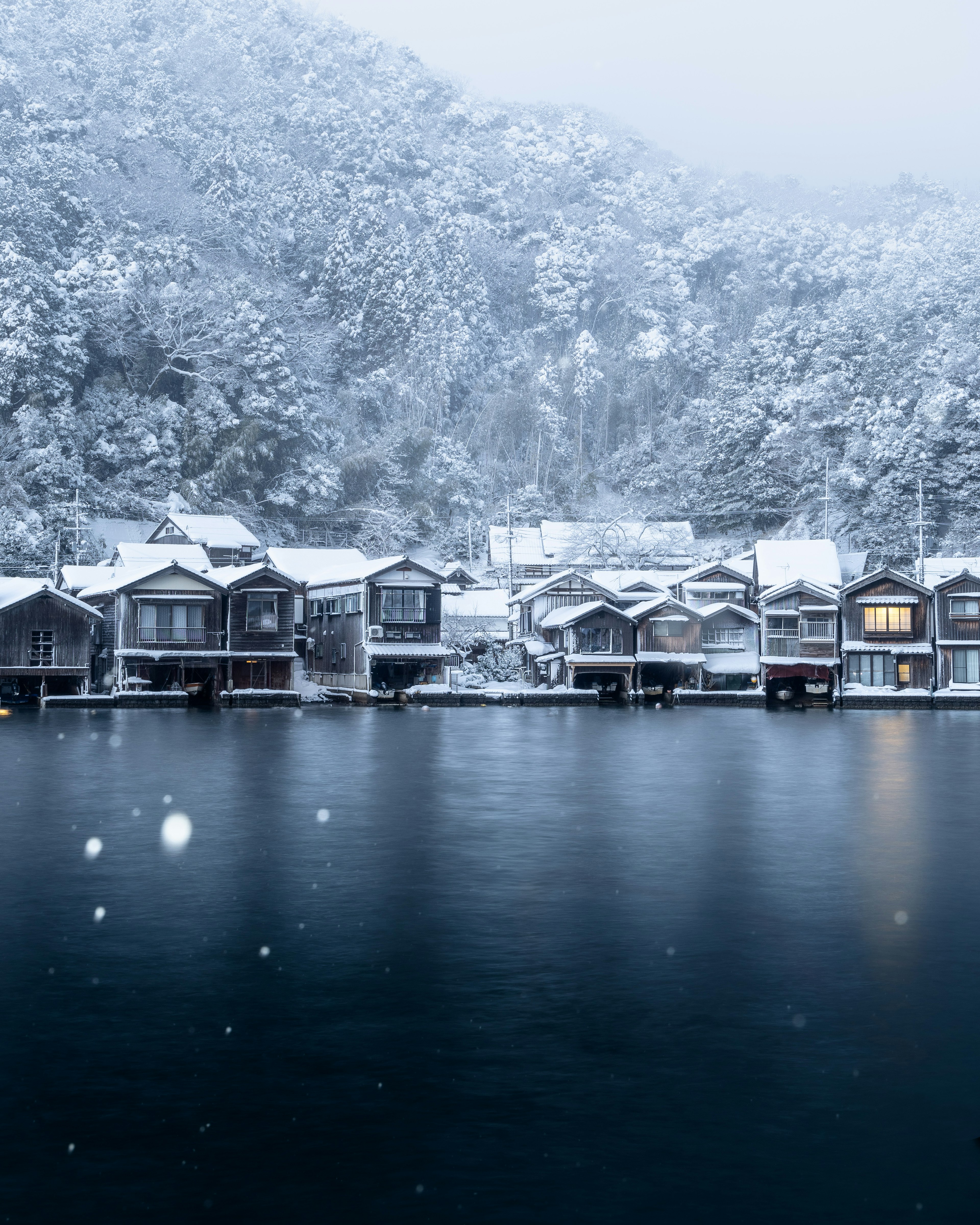 ทิวทัศน์ริมทะเลสาบที่เงียบสงบพร้อมกระ cabin ที่ปกคลุมด้วยหิมะ