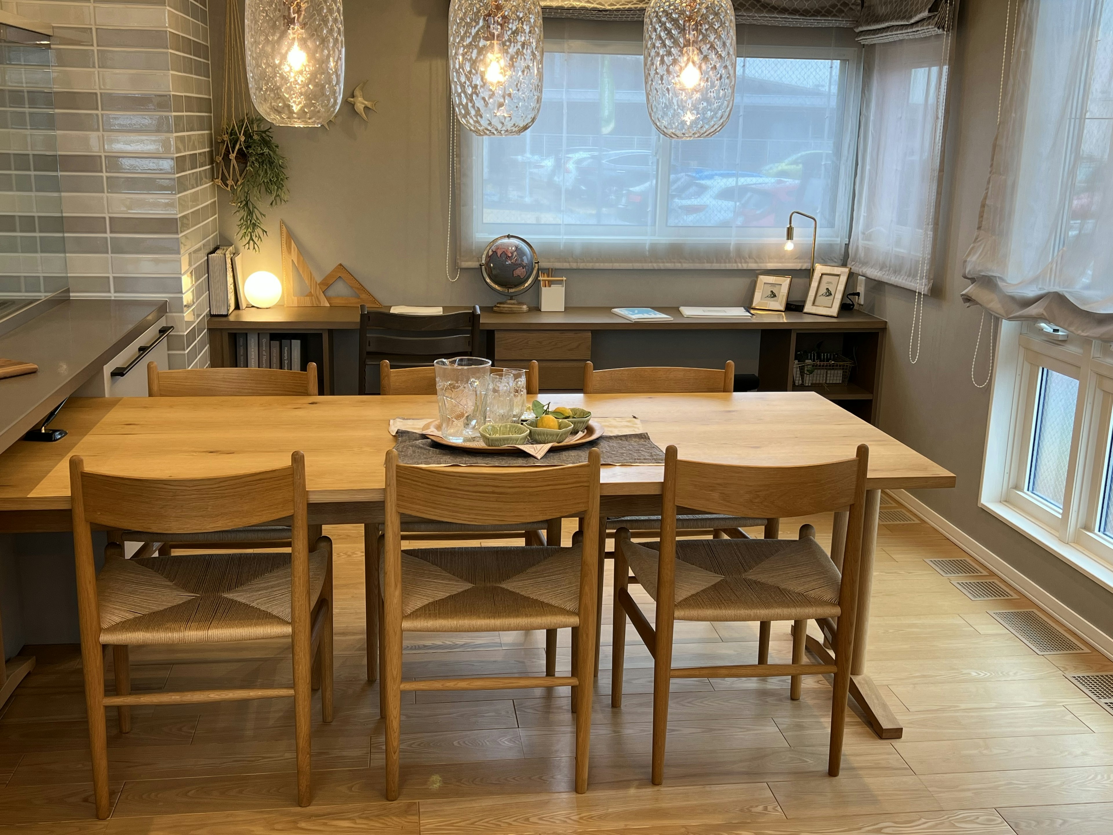 Brillante comedor con mesa y sillas de madera, iluminación simple y luz natural de las ventanas