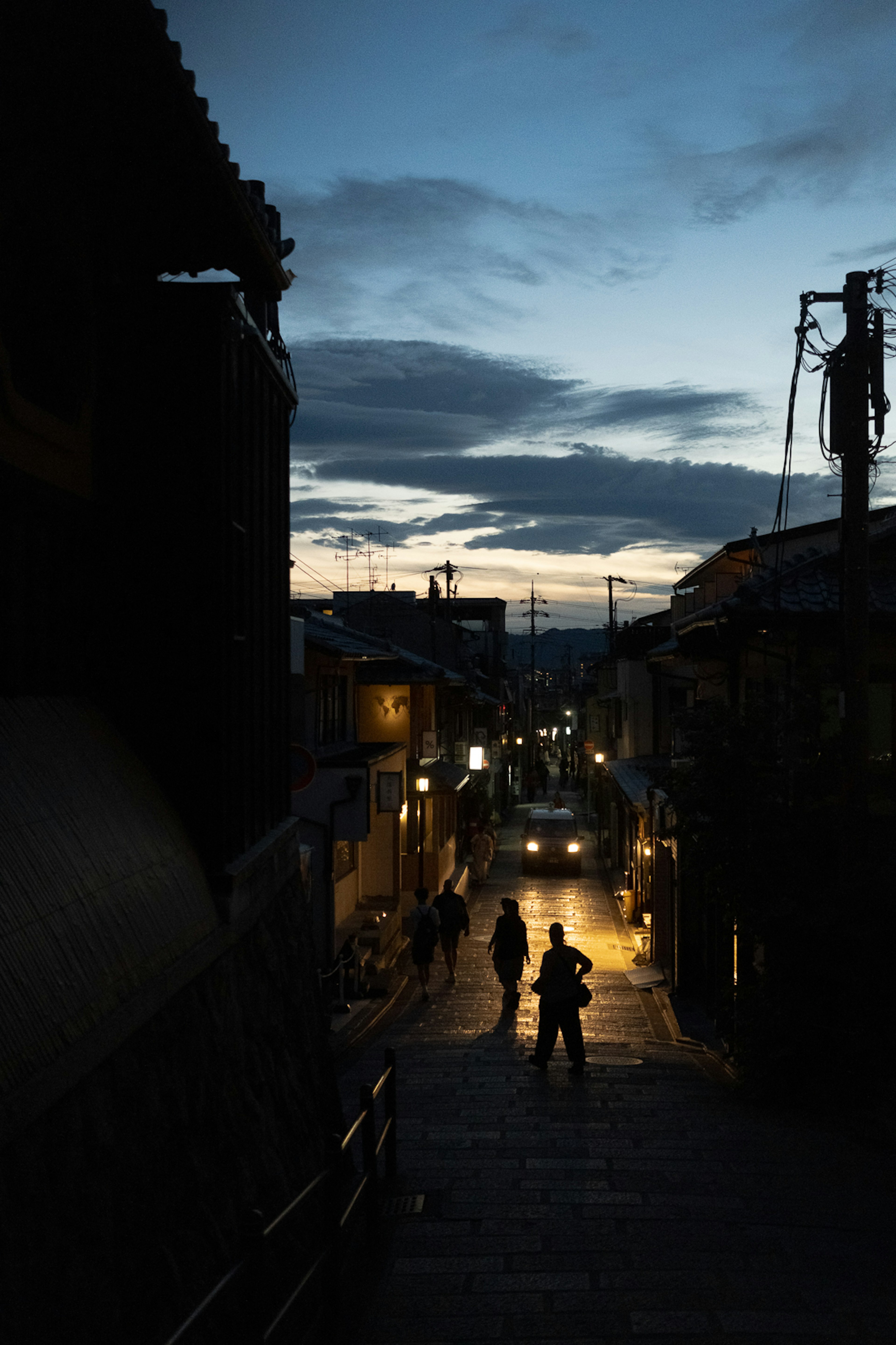 Silhouettes of people walking in a quiet street at dusk