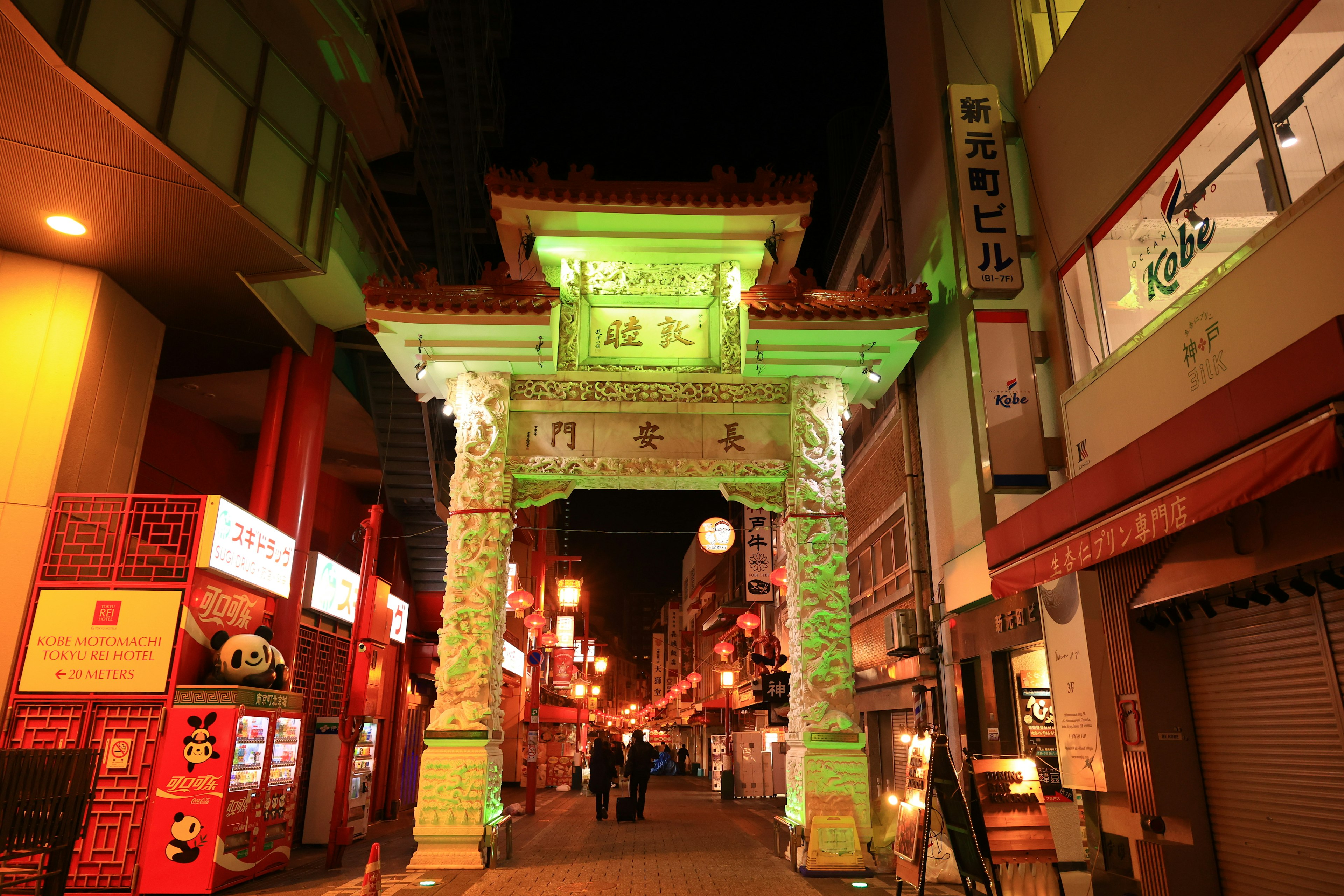 Vista nocturna de la puerta de arco verde en Chinatown de Yokohama con calle iluminada