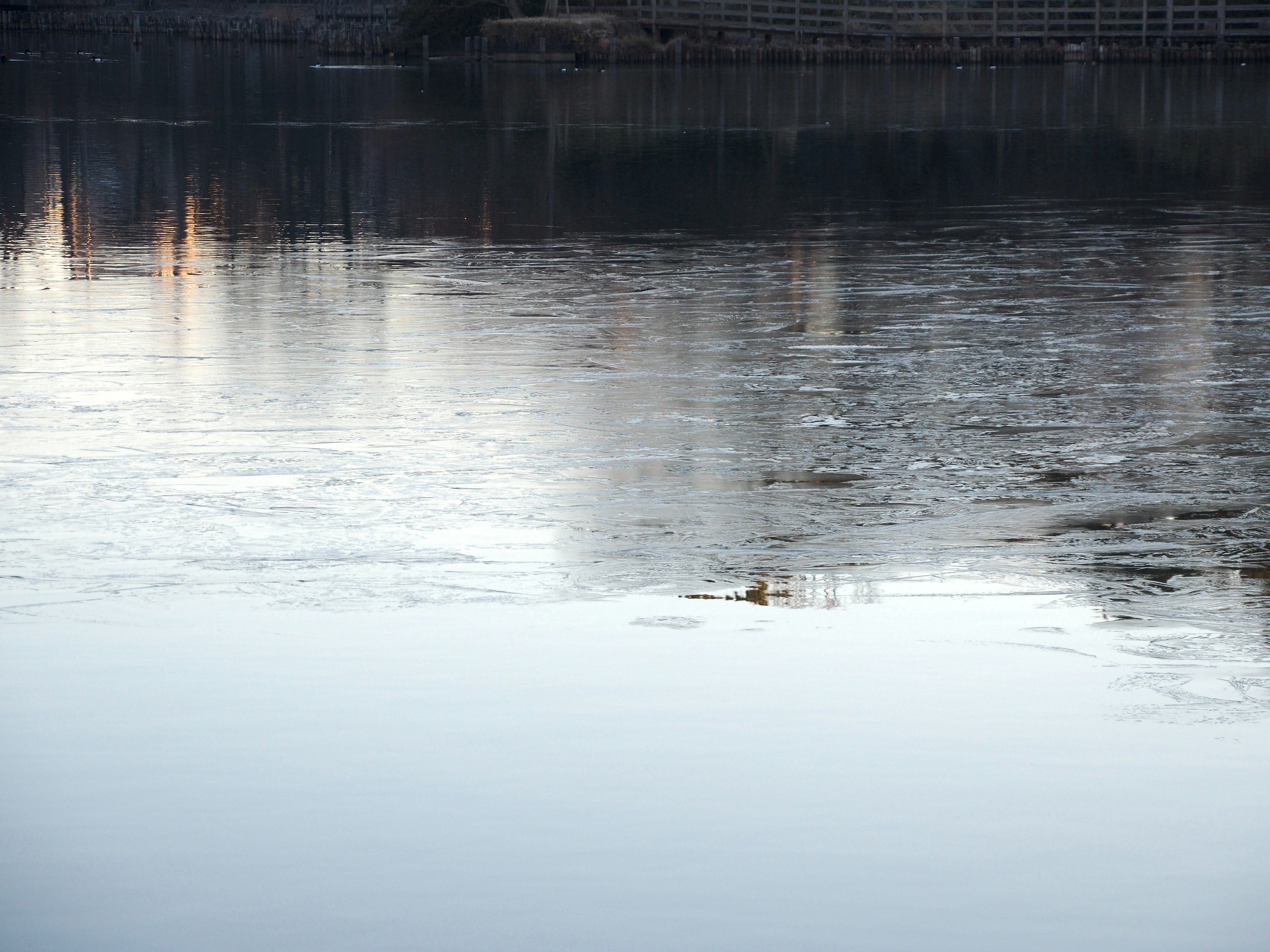 Ruhige Wasseroberfläche, die Gebäude und eisige Landschaft reflektiert