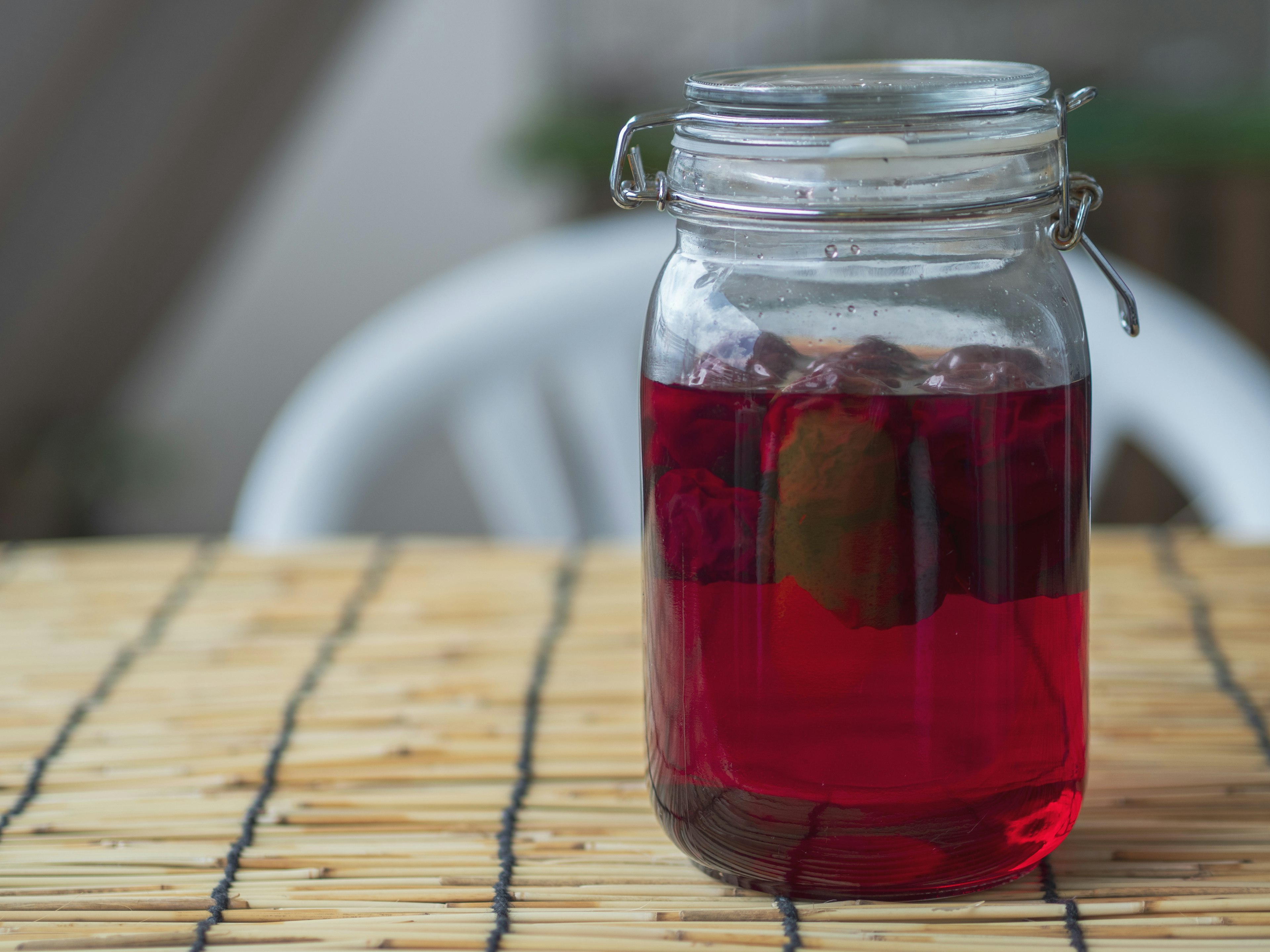 Bocal en verre avec une boisson rouge sur une table en bois