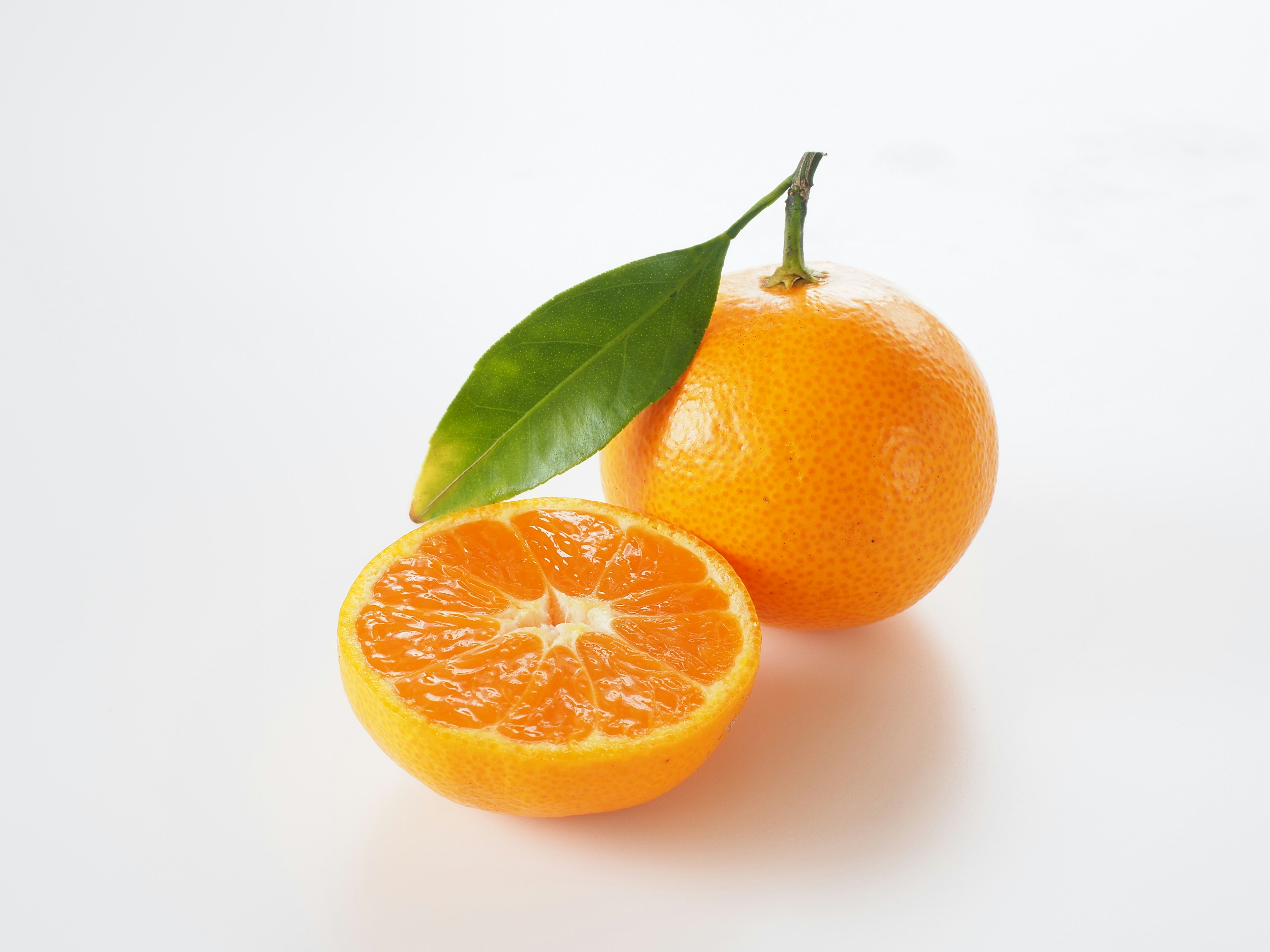 Fresh orange and its half placed on a white background