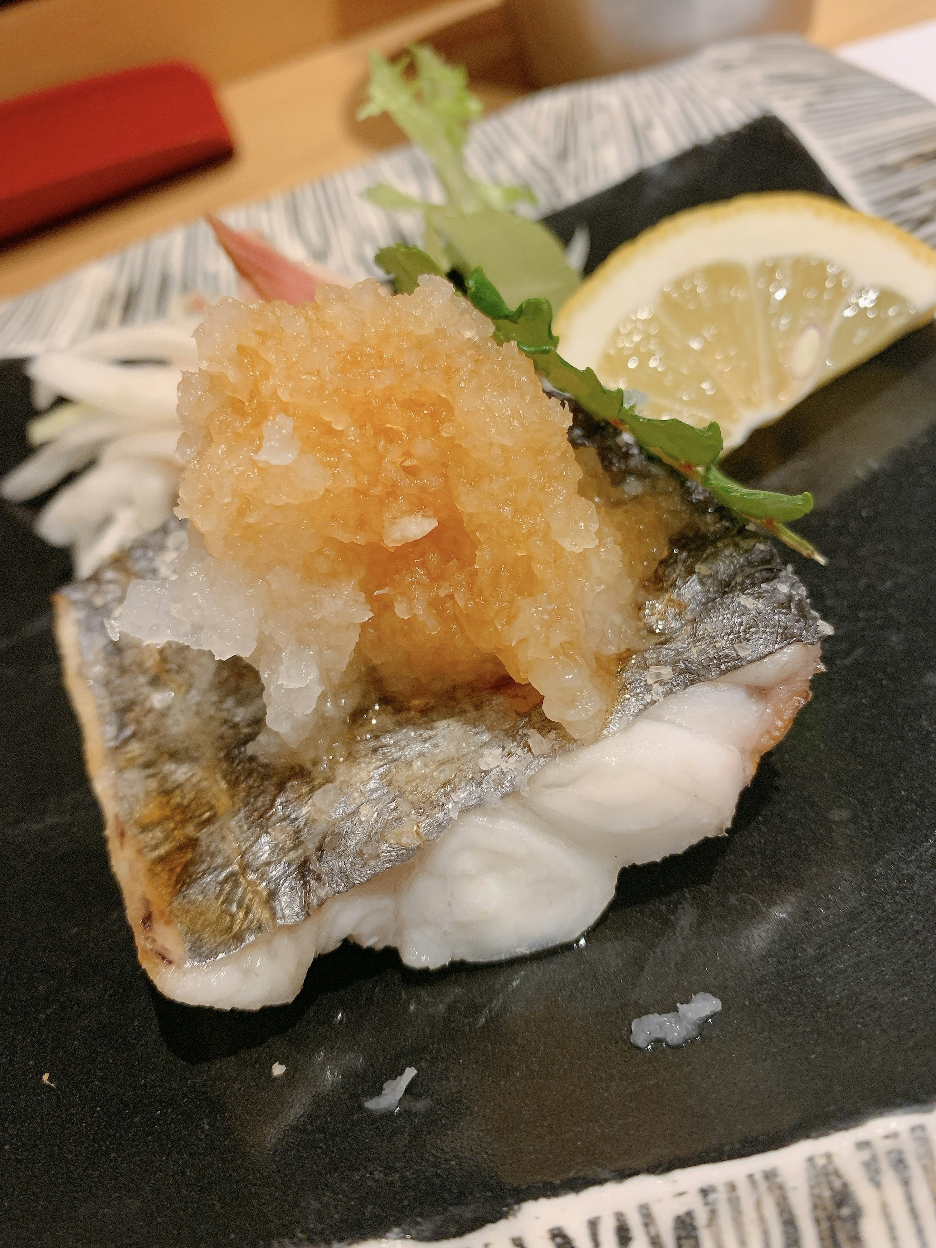 Plato de cocina japonesa con pescado en rodajas cubierto de daikon rallado y decorado con limón