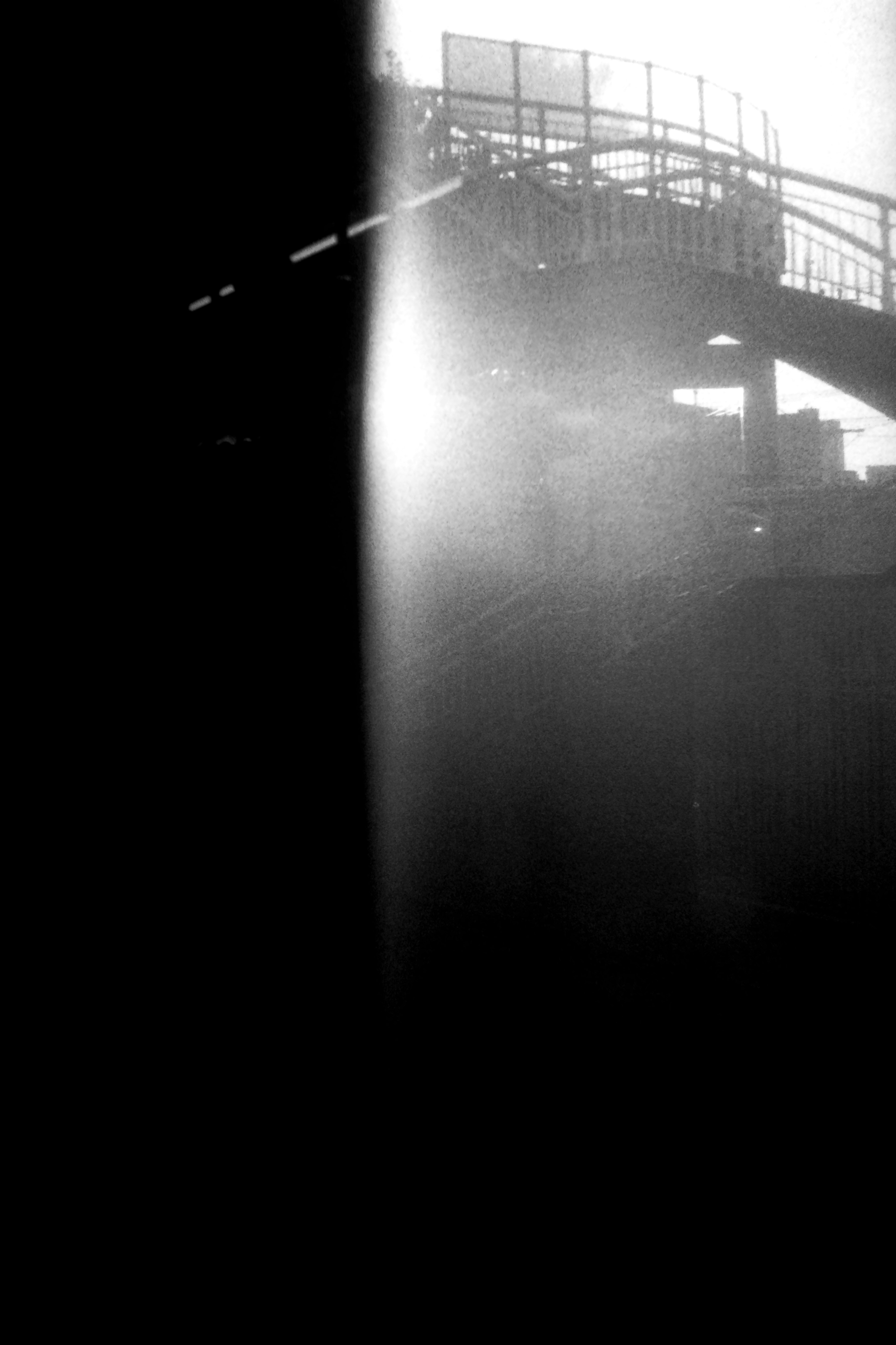 Black and white photo featuring a bridge structure illuminated by soft light