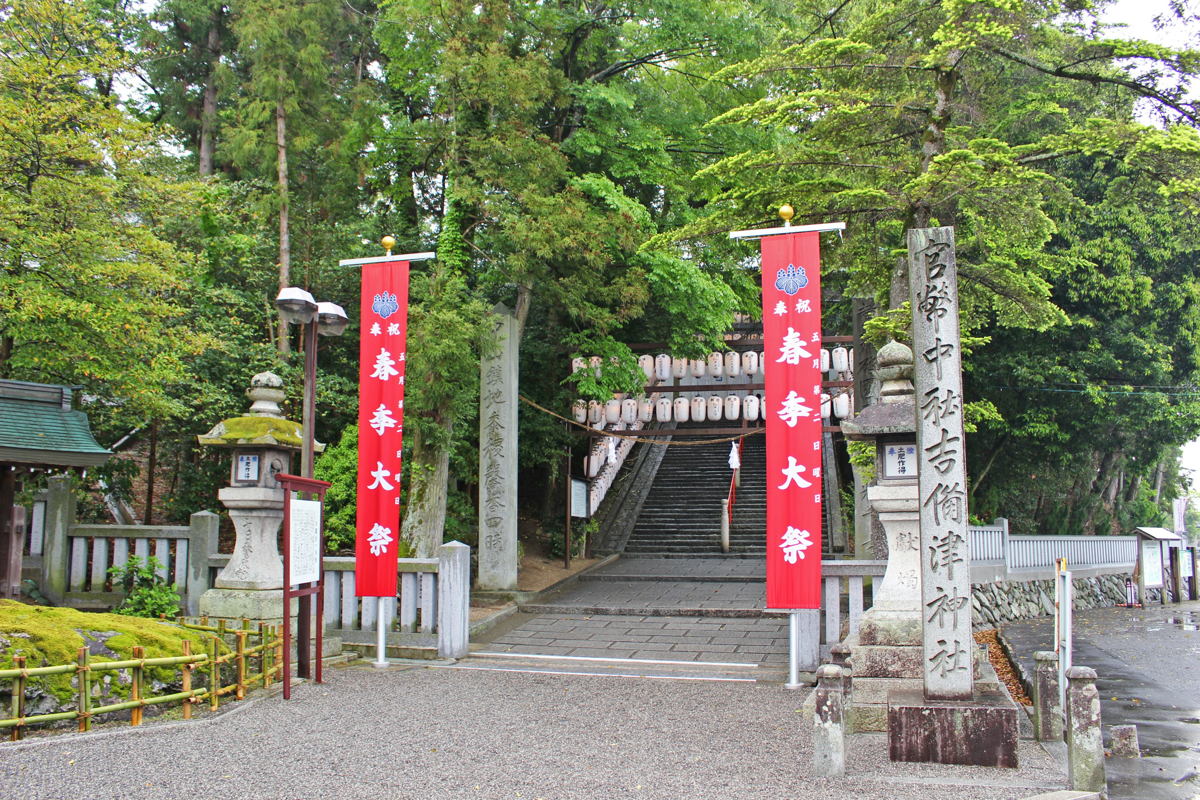 Entrata di un santuario con bandiere rosse e un torii in pietra