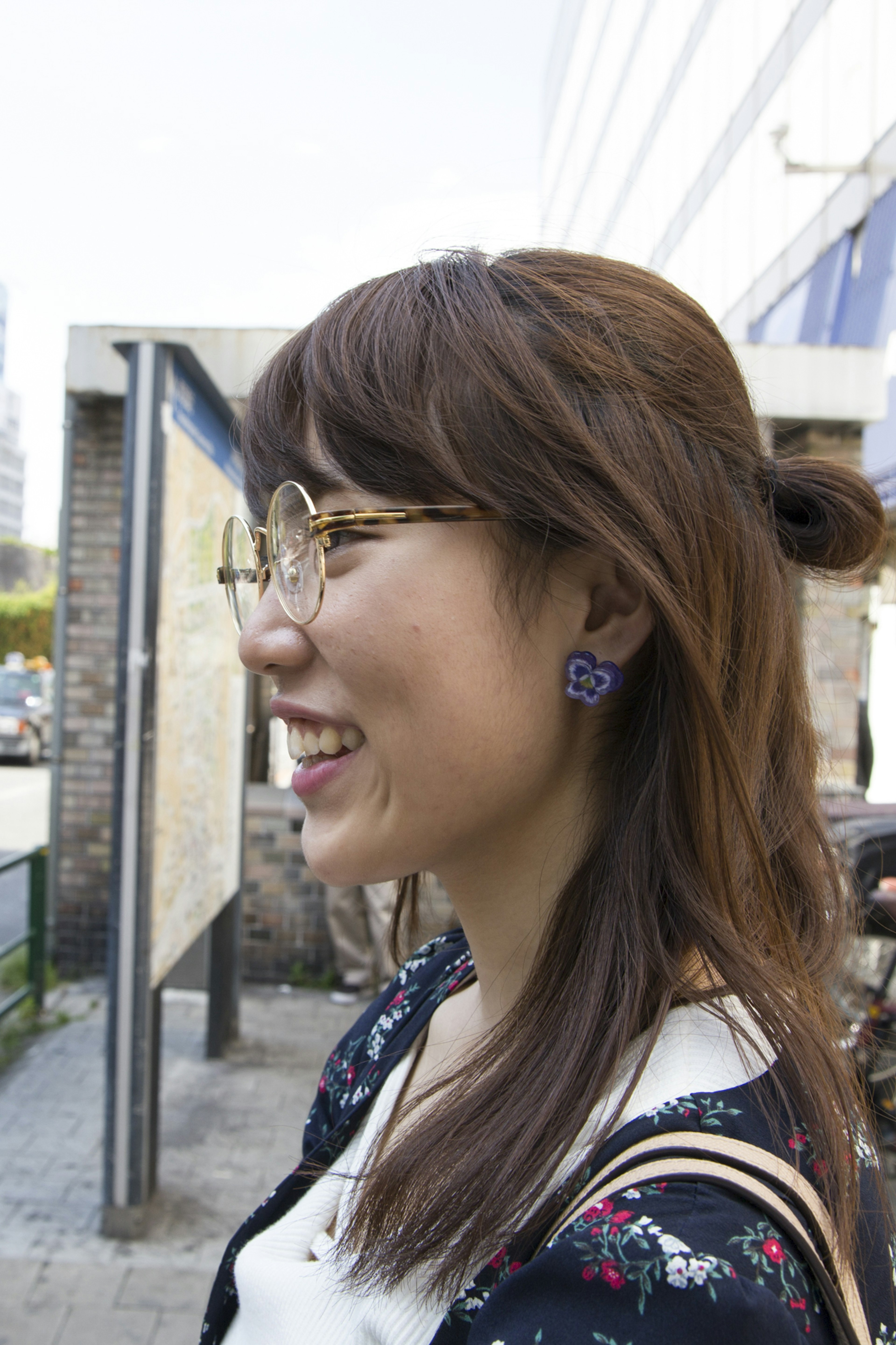 Profile of a woman smiling wearing glasses and earrings