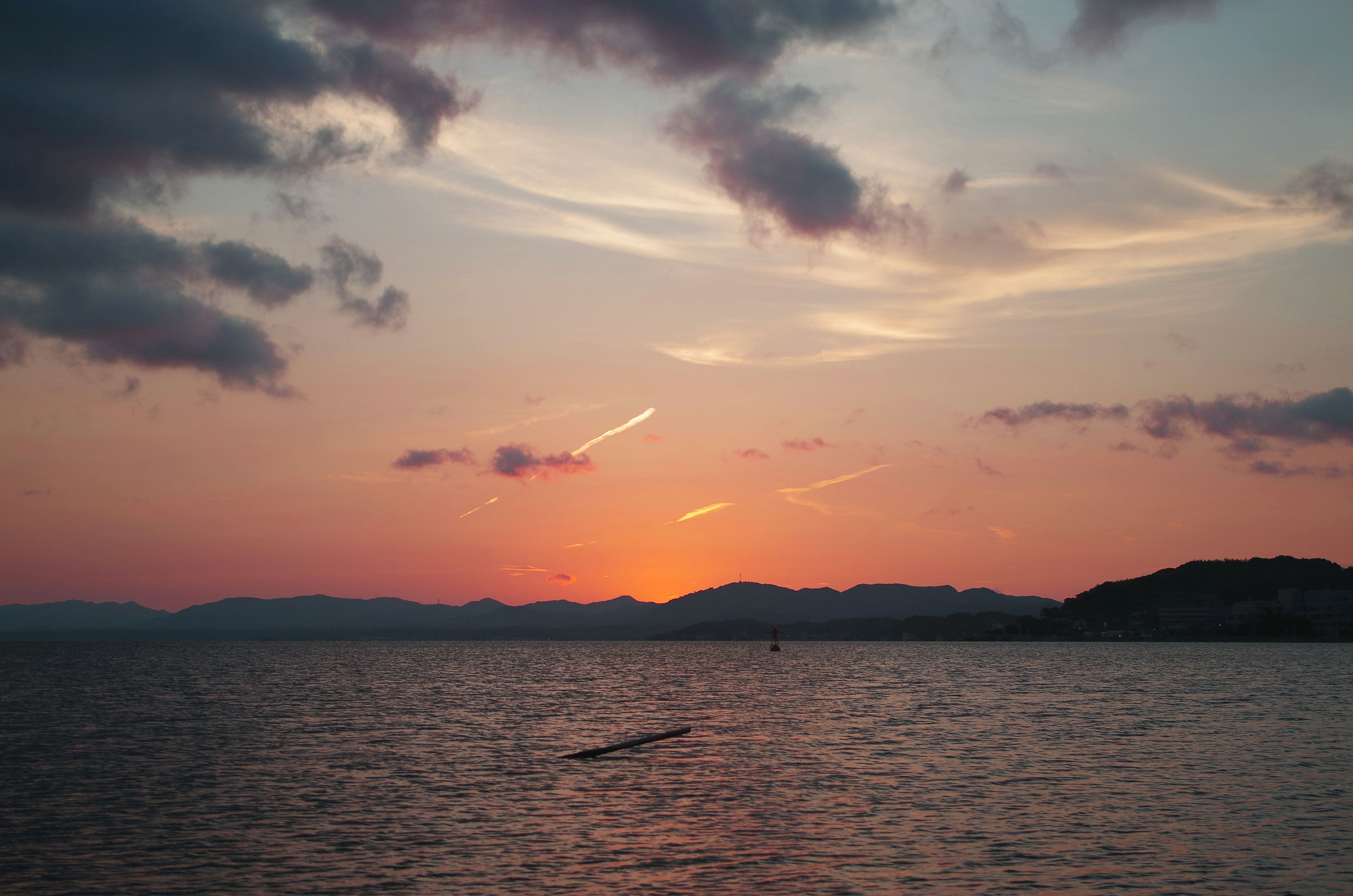 夕焼けの海と山の景色　オレンジと青の空　雲が漂う