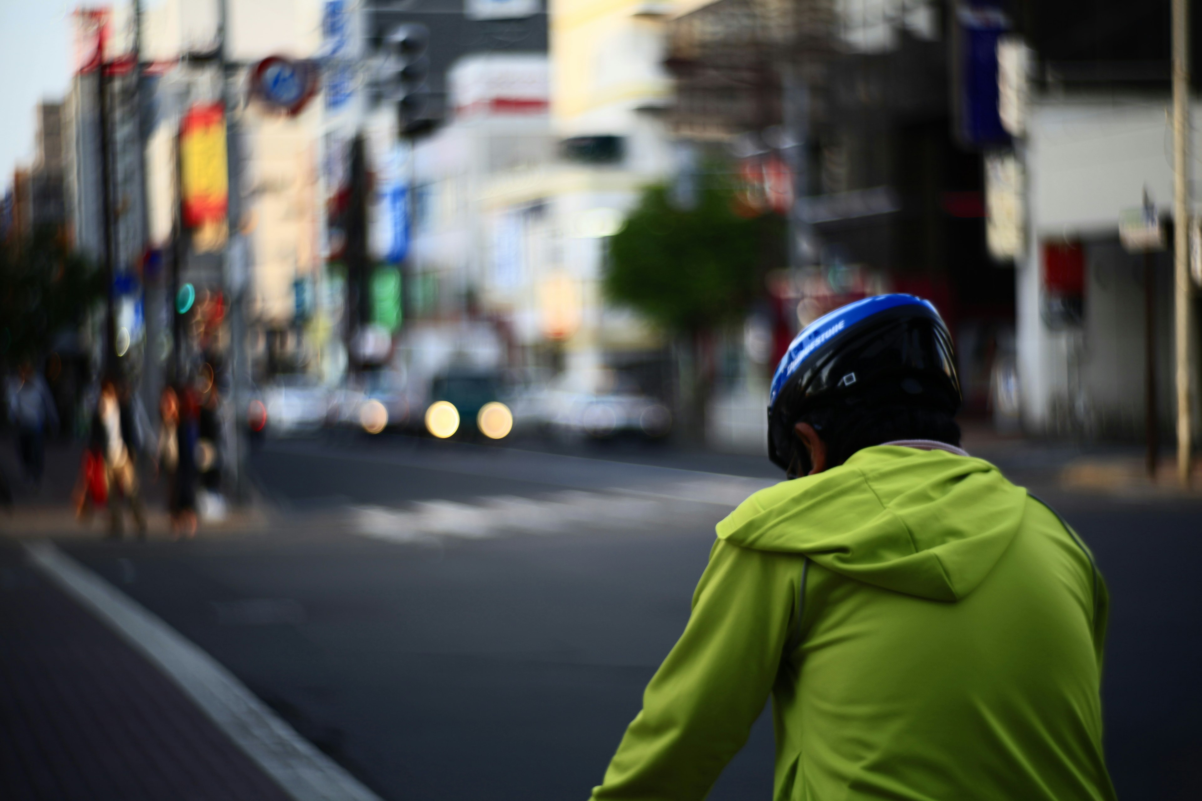 Ein Radfahrer in einer leuchtend grünen Jacke und einem Helm, der die verschwommene Stadtlandschaft betrachtet