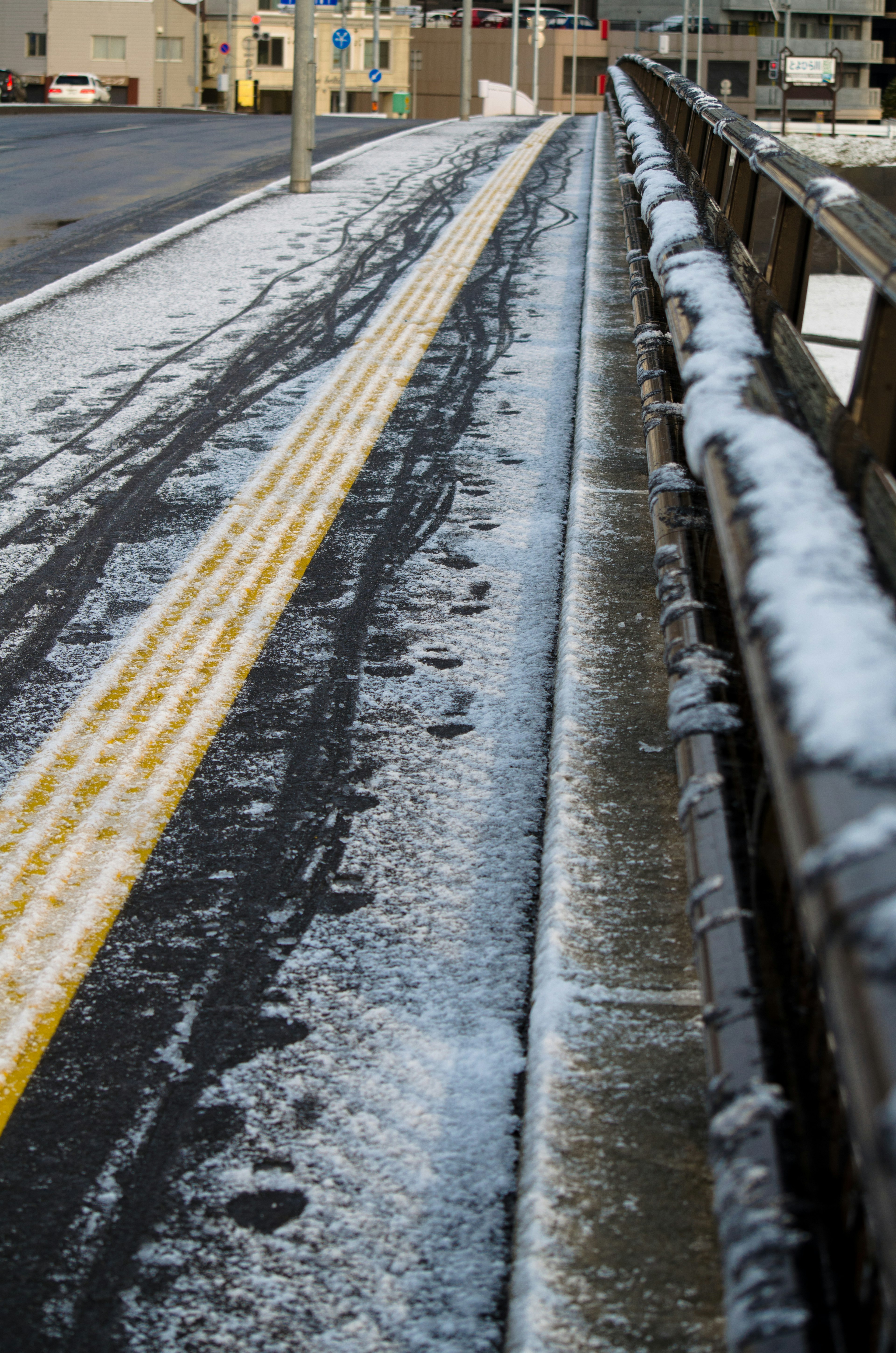 Sentiero pavimentato coperto di neve con una ringhiera di legno e impronte di pneumatici