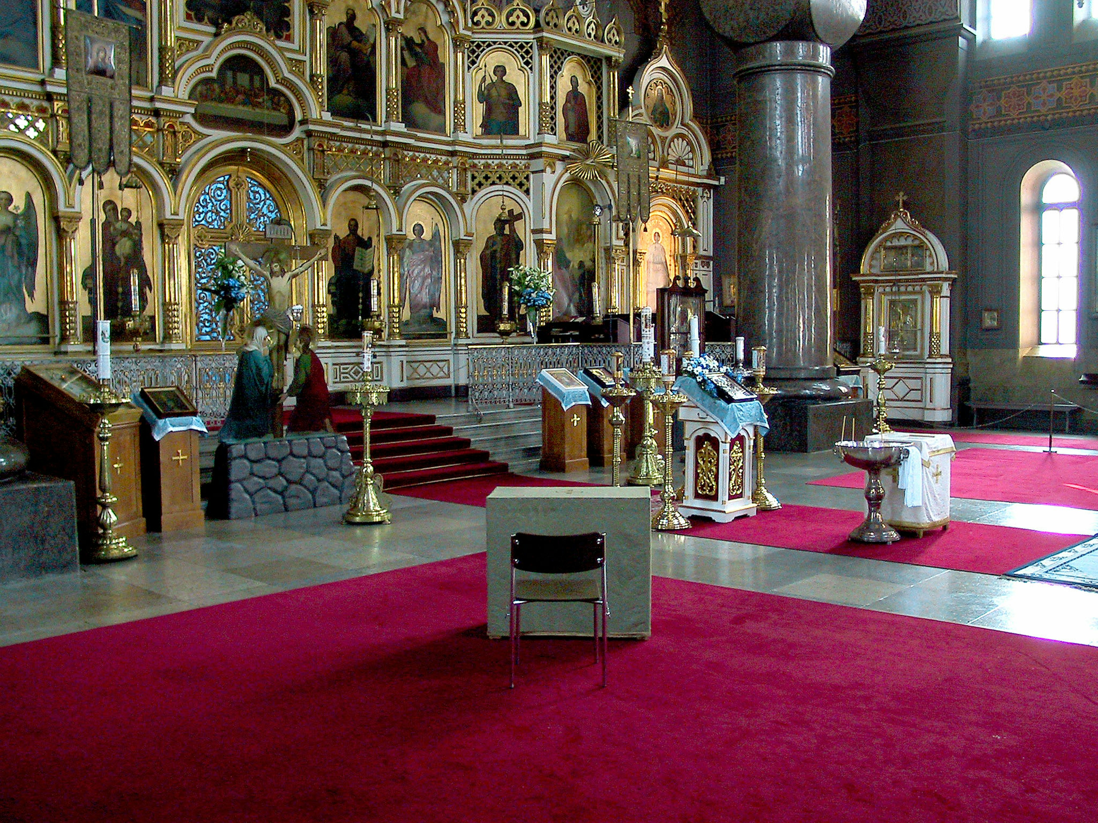 Innenraum einer Kirche mit rotem Teppich und einem wunderschön dekorierten Altar sowie Statuen